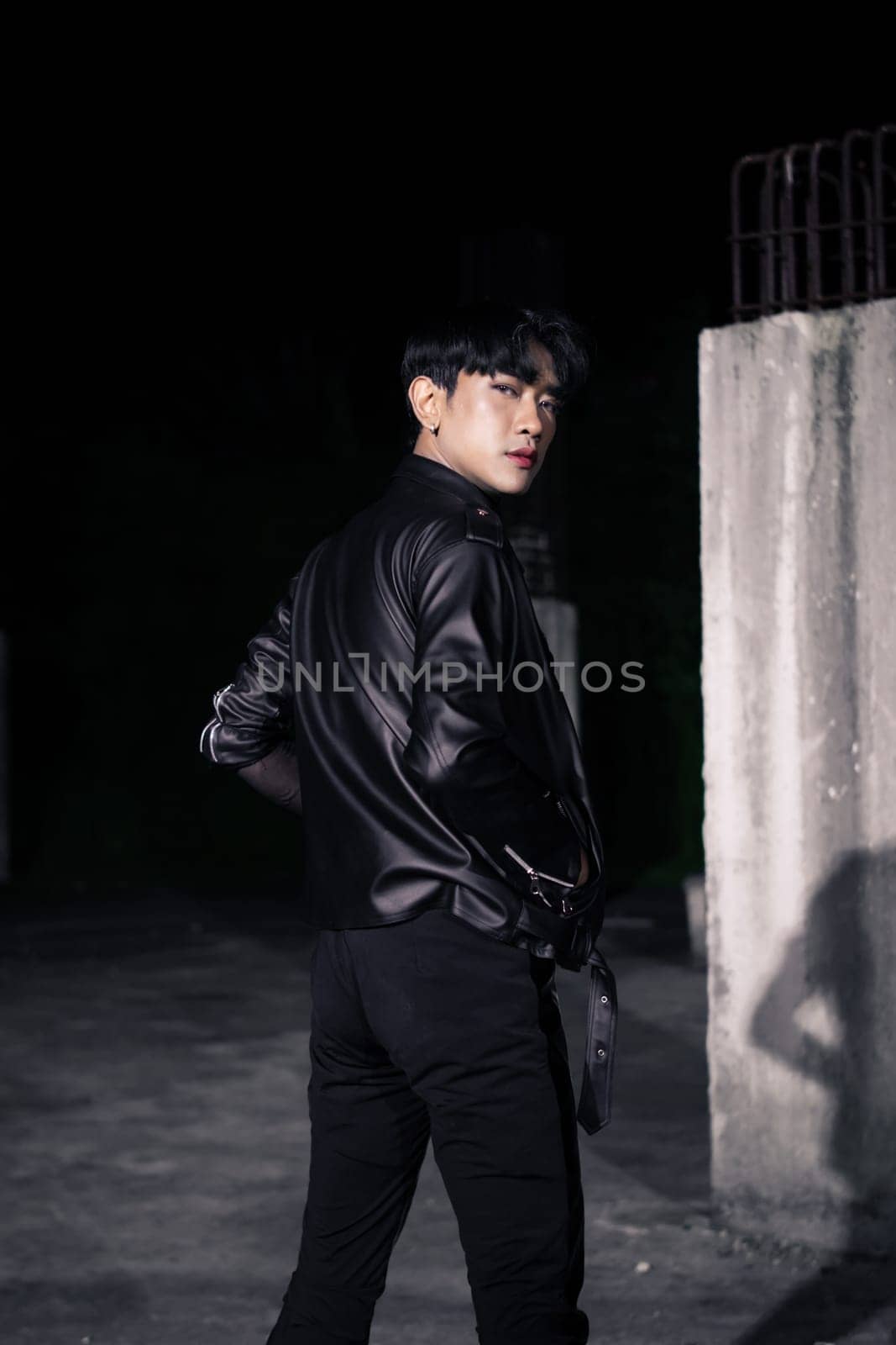 an asian man in a black leather jacket posing like a motorcycle gang in an old building