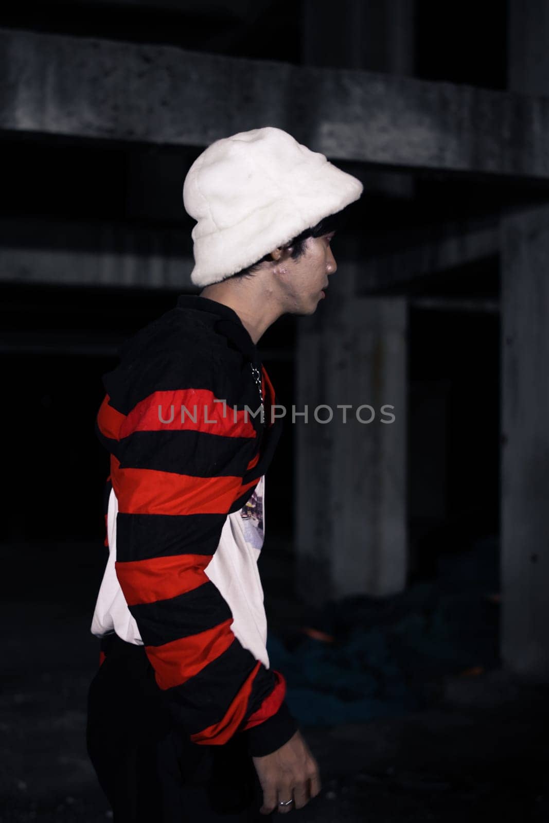 an Asian man is standing in a crimson outfit and a white hat in a haunted building