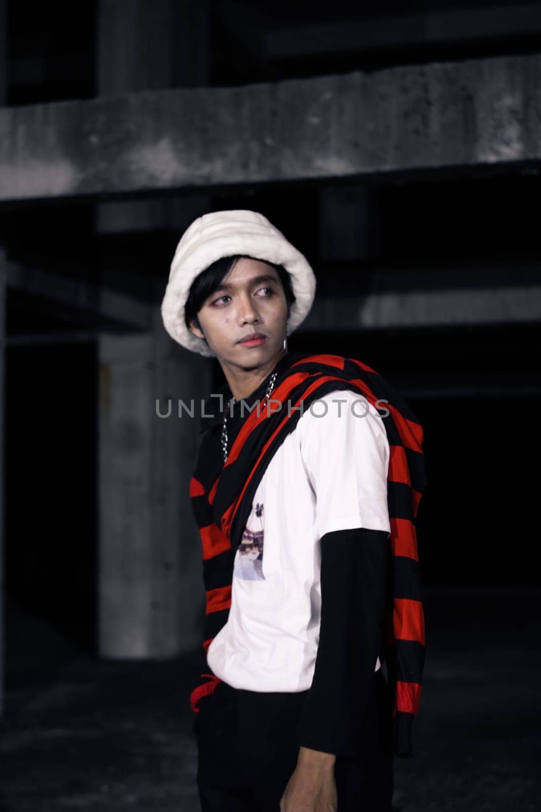 an Asian man is standing in a crimson outfit and a white hat in a haunted building