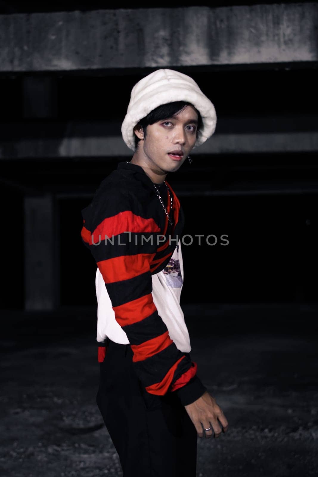 an Asian man is standing in a crimson outfit and a white hat in a haunted building