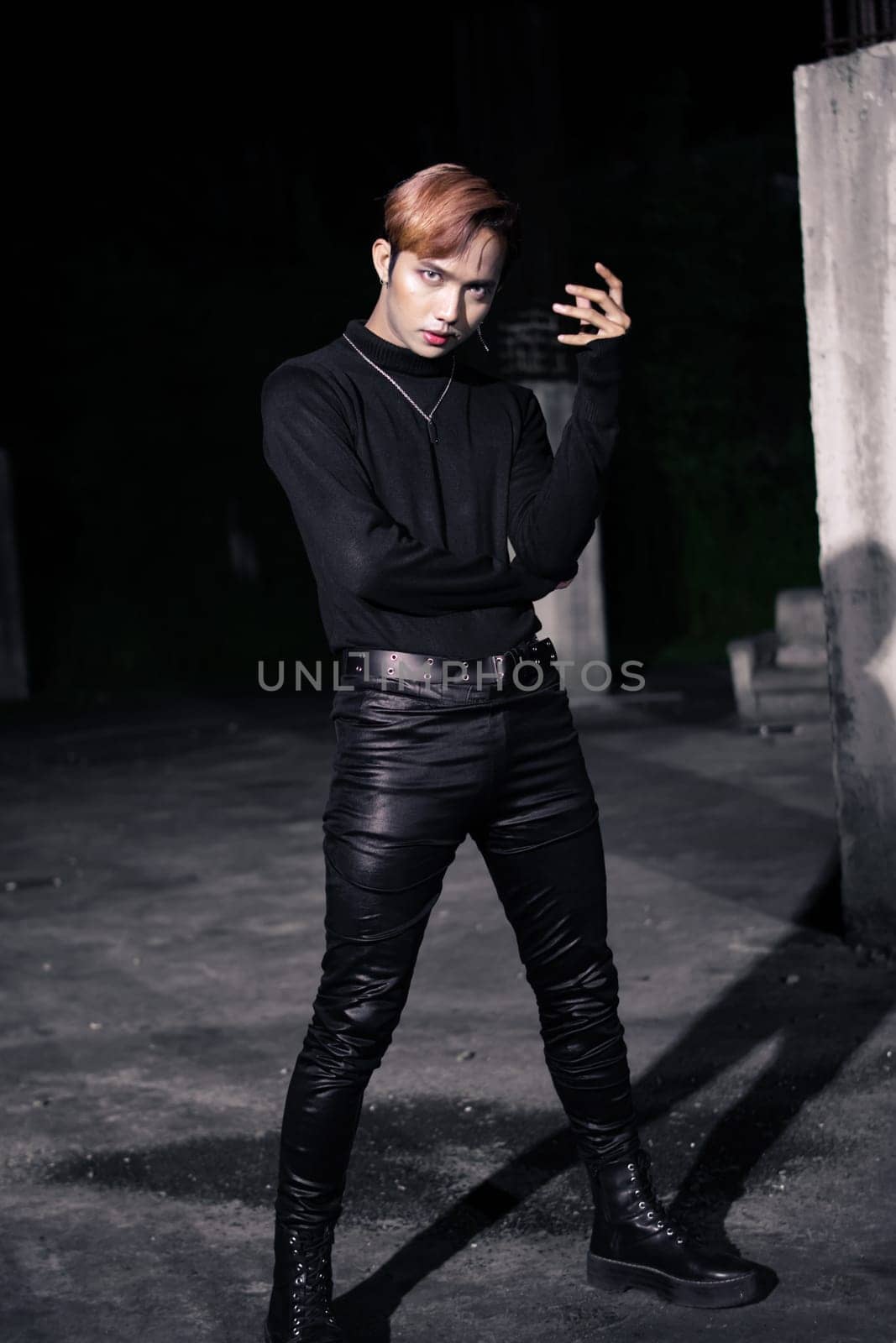 an Asian man with blond hair wearing tight black pants and a black shirt in a building