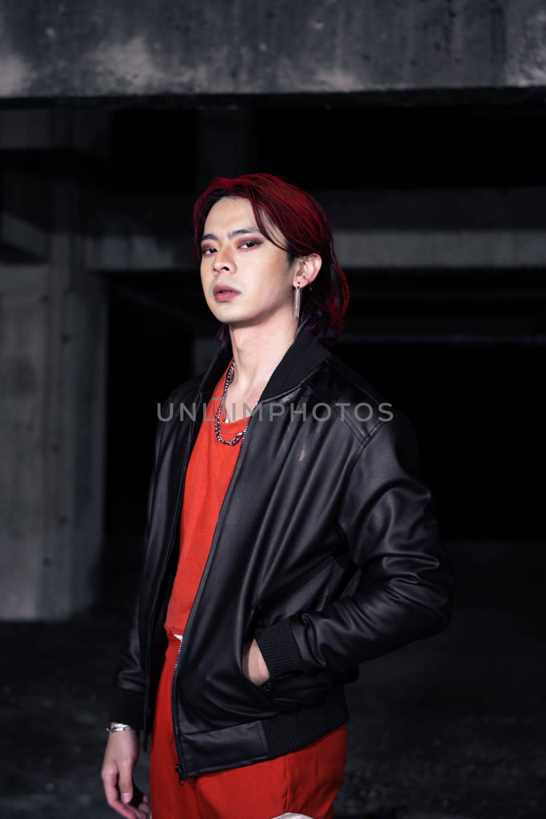 an asian man with red hair and a black jacket is posing in an abandoned building at night