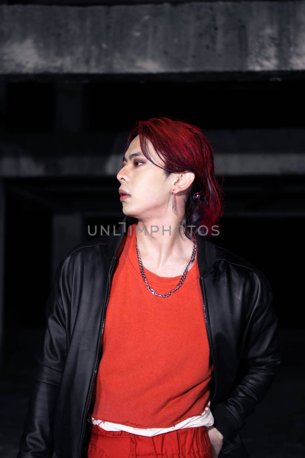 an asian man with red hair and a black jacket is posing in an abandoned building at night
