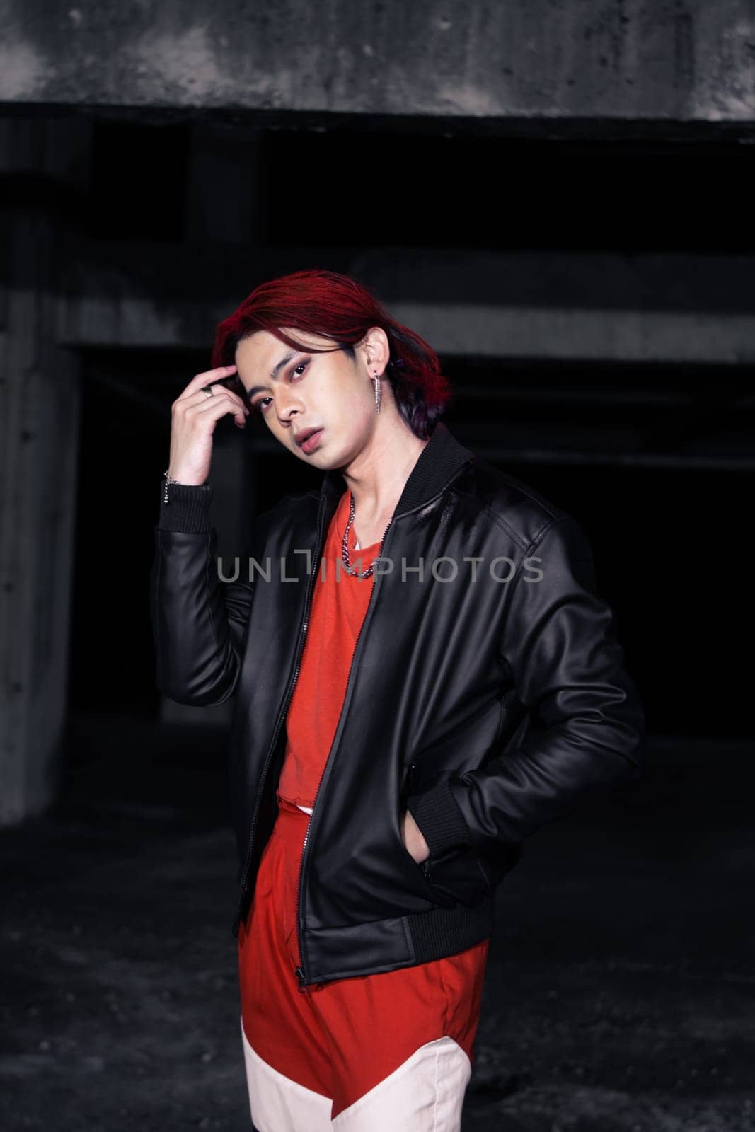an asian man with red hair and a black jacket is posing in an abandoned building at night