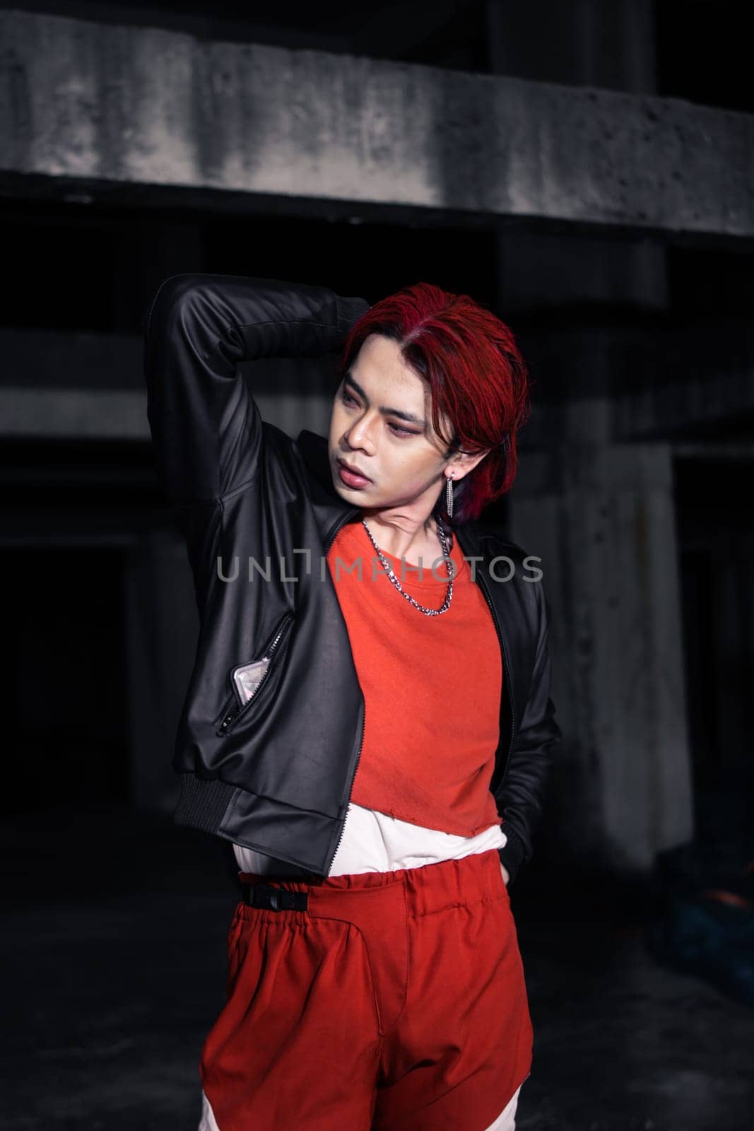 an asian man with red hair and a black jacket is posing in an abandoned building at night