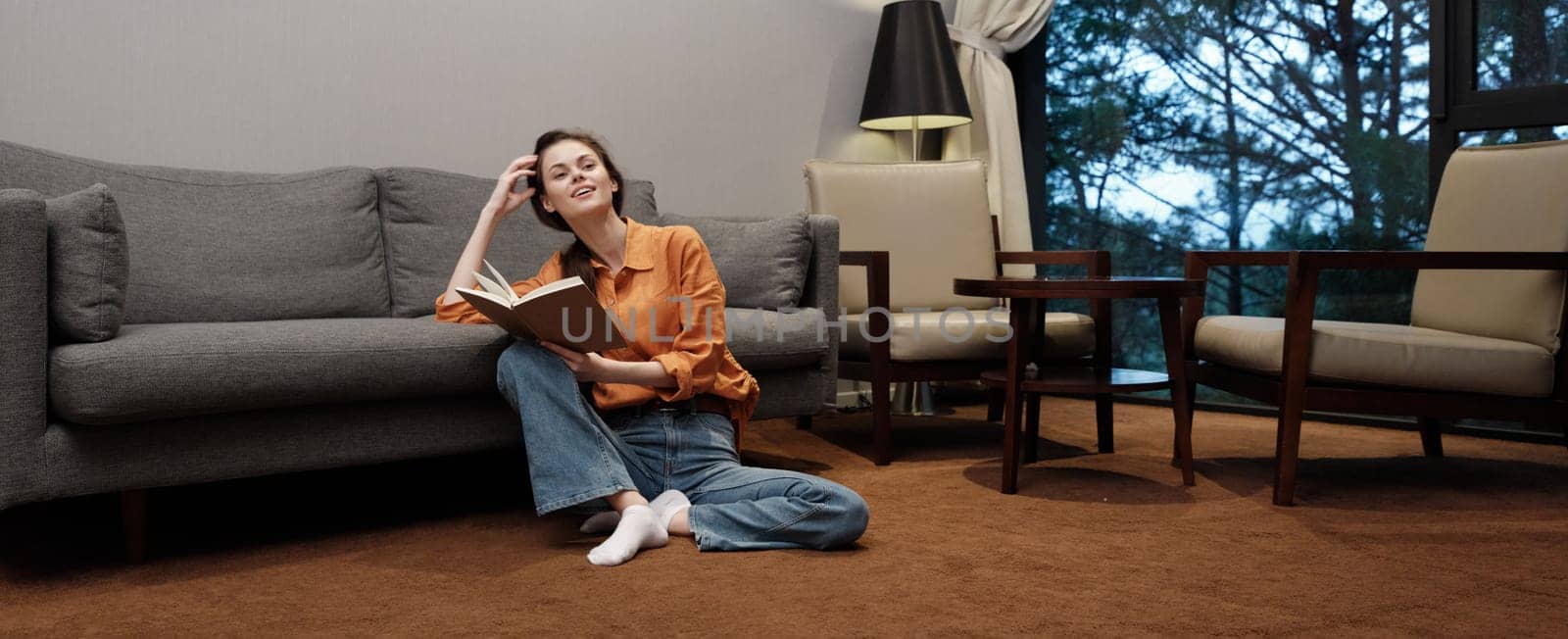 A relaxed young woman is enjoying a book in a warm, cozy living room The scene conveys tranquility and comfort with warm colors and soft lighting, ideal for wellness themes