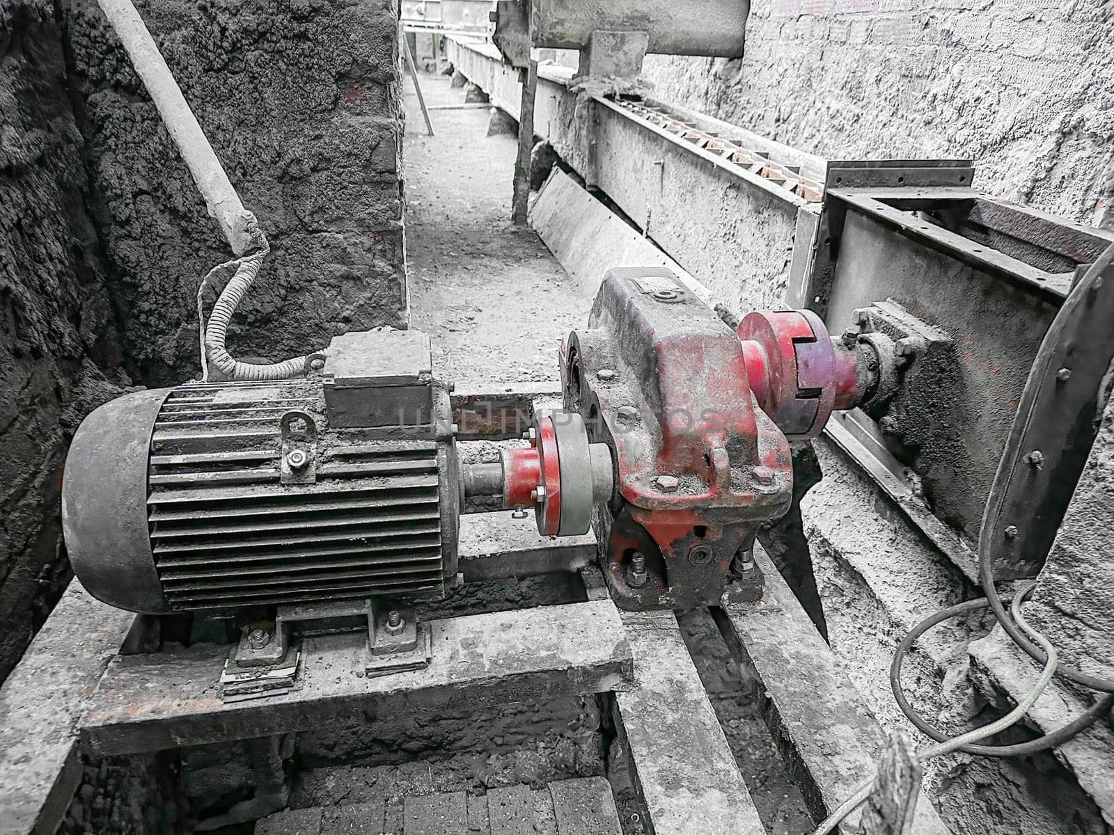 A motor and pump system is installed within an industrial facility. The machinery is set up on hardwood beams, showcasing the operational components during a busy workday in the factory.