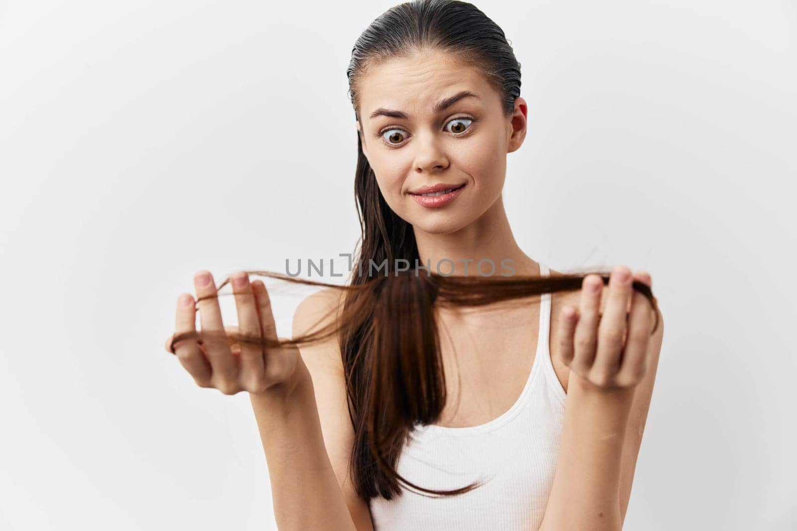 surprised woman examining her own hair with a shocked expression, holding a long strand of brown hair Compact and minimalist background highlights her emotional reaction to hair loss