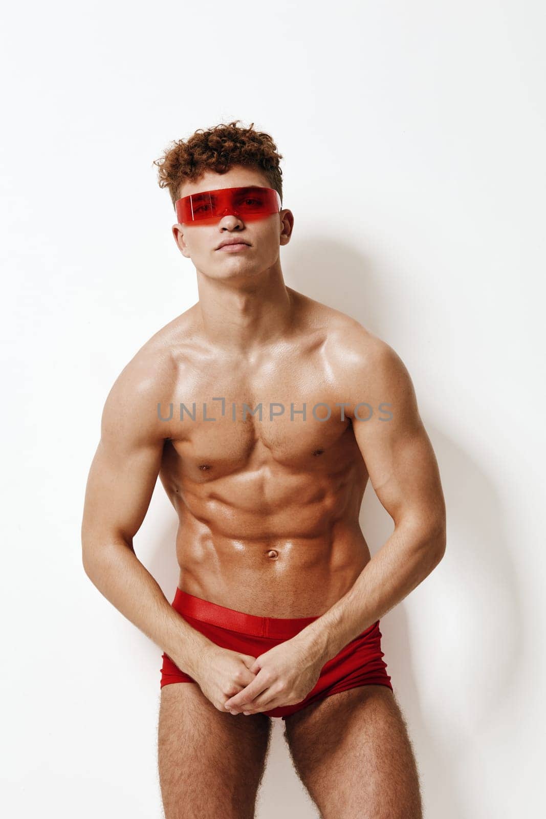 Stylish male model with curly hair stands confidently against a neutral background, radiating an energetic and captivating vibe. Modern fashion and confidence theme.