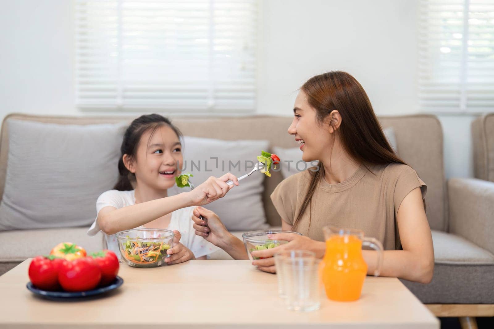 A delightful moment as a mother and daughter share healthy salads, illustrating the importance of wellness and family bonding over nutritious food.