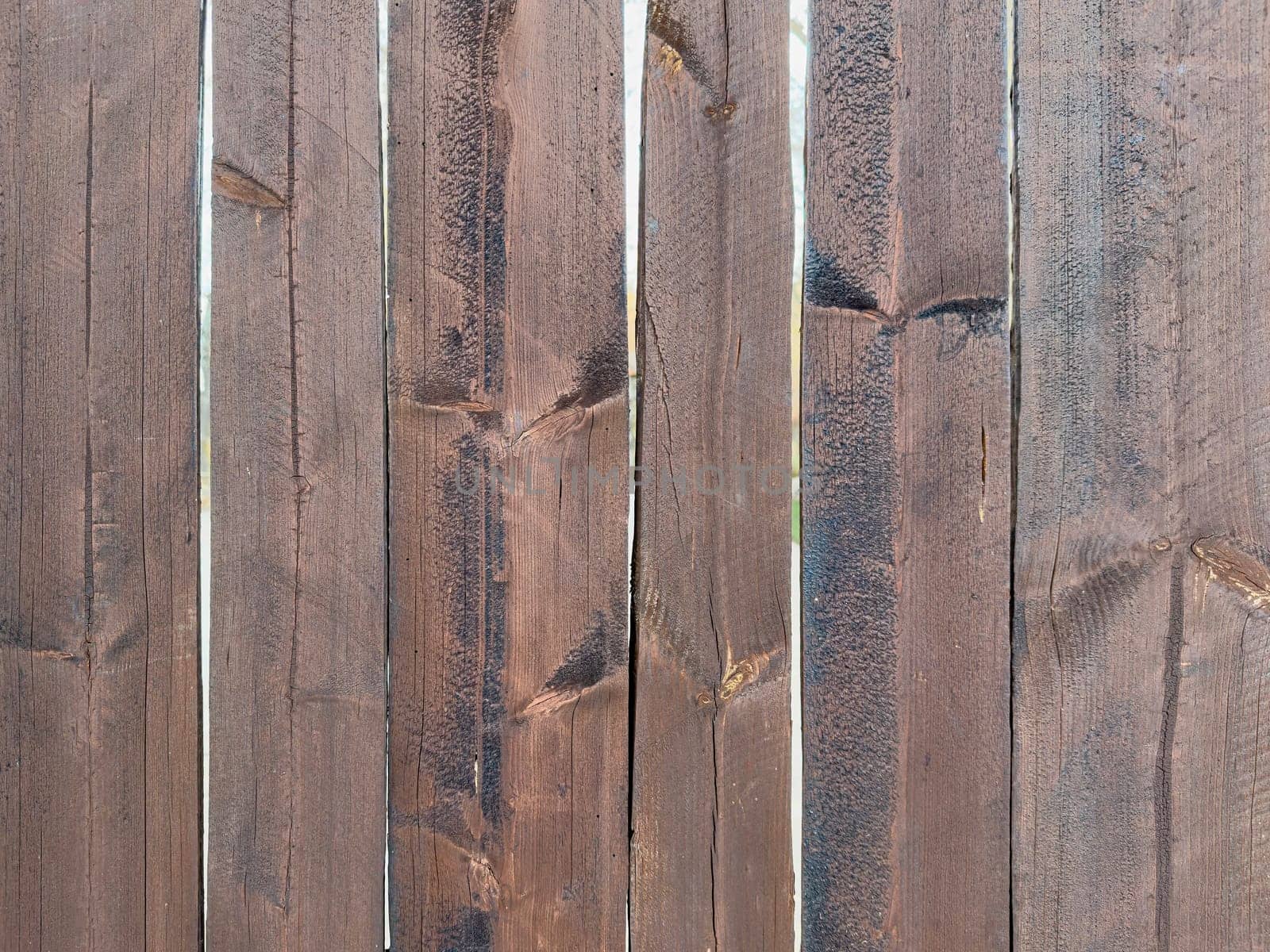 Close-up view of a wooden fence showcasing various shades of brown. Each slat exhibits unique patterns and textures, revealing the natural beauty of the wood grain.
