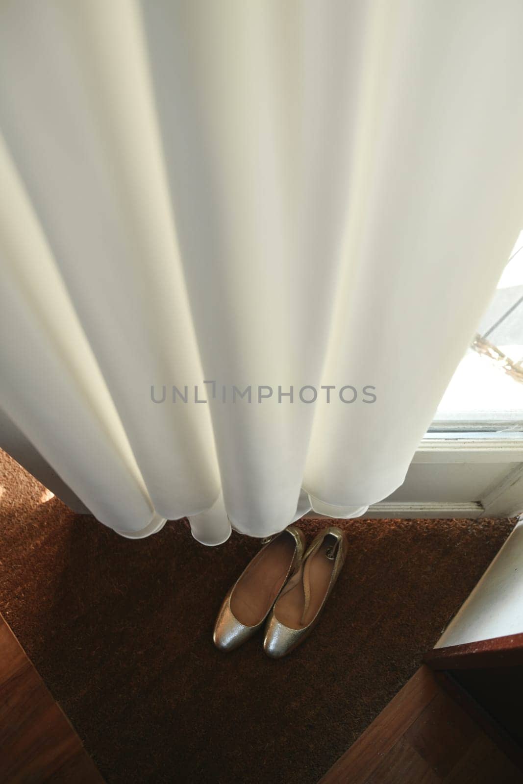 The Wedding dress hanging on the door and golden shoes