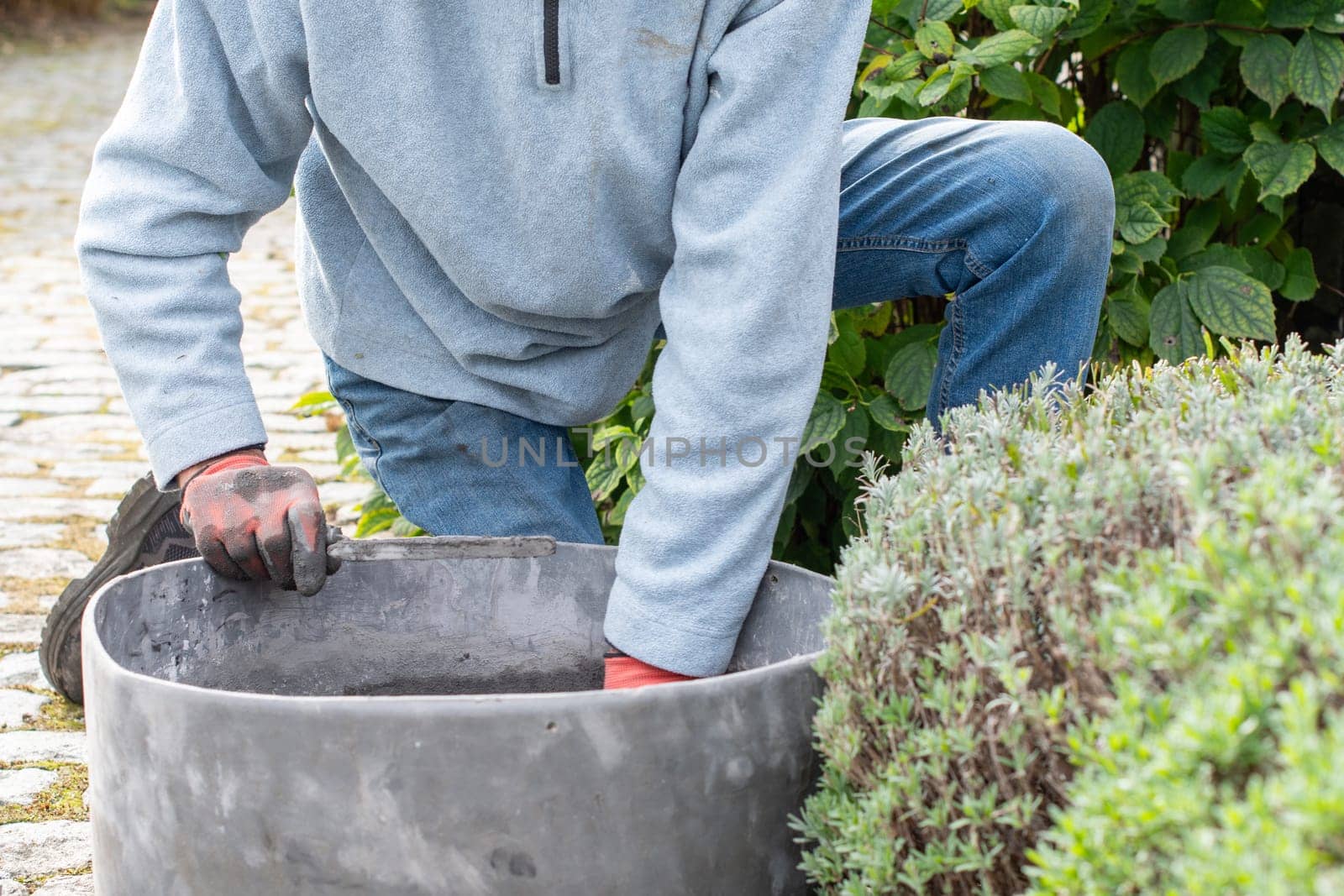 Experienced builder wearing gloves mixes cement mortar in a special tatsu, thoroughly mixing cement, sand and water, ensuring the optimum texture for a strong bond between the bricks,