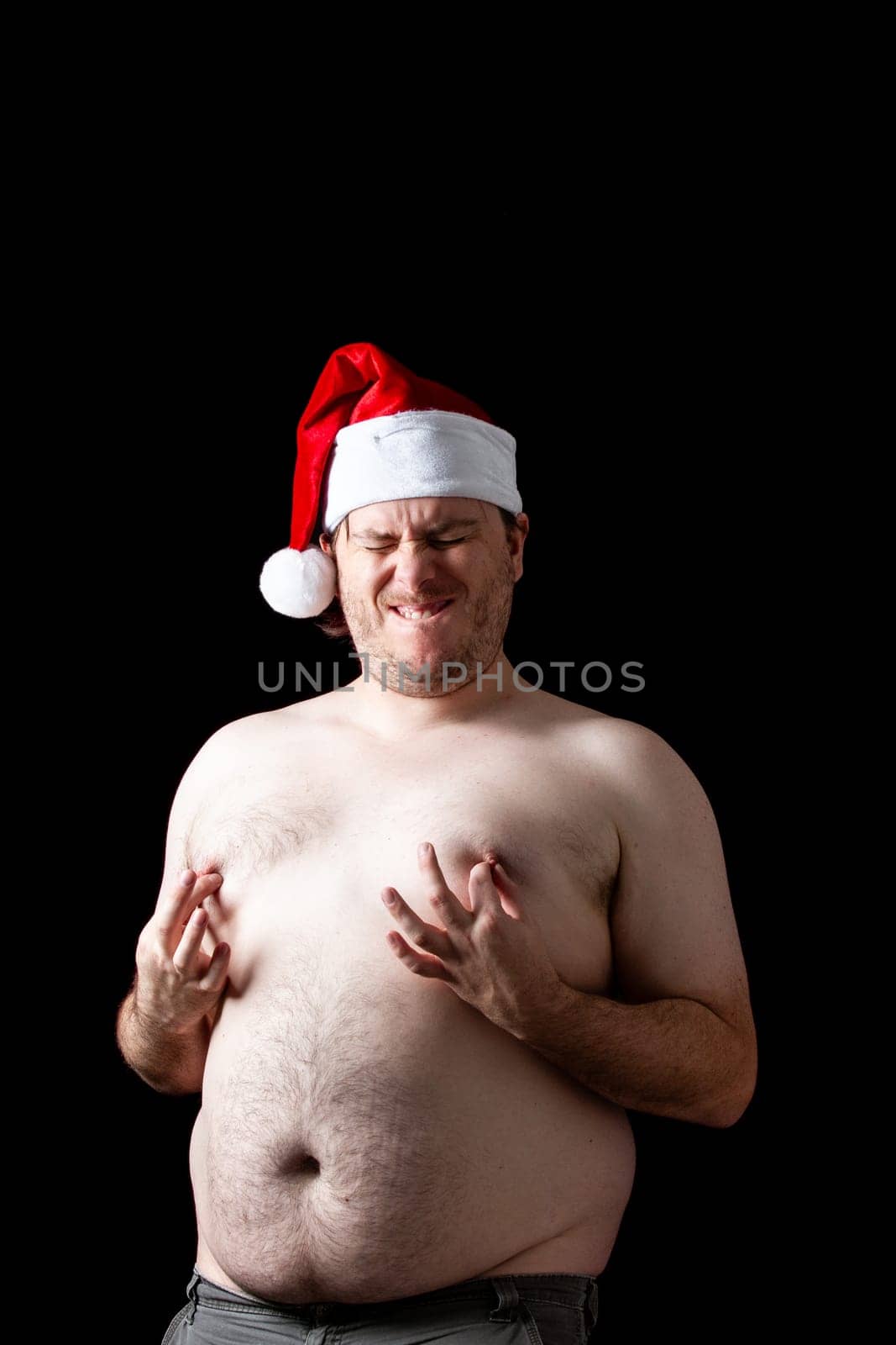 A man is wearing a Santa hat and is showing his chest. The image has a humorous and lighthearted mood