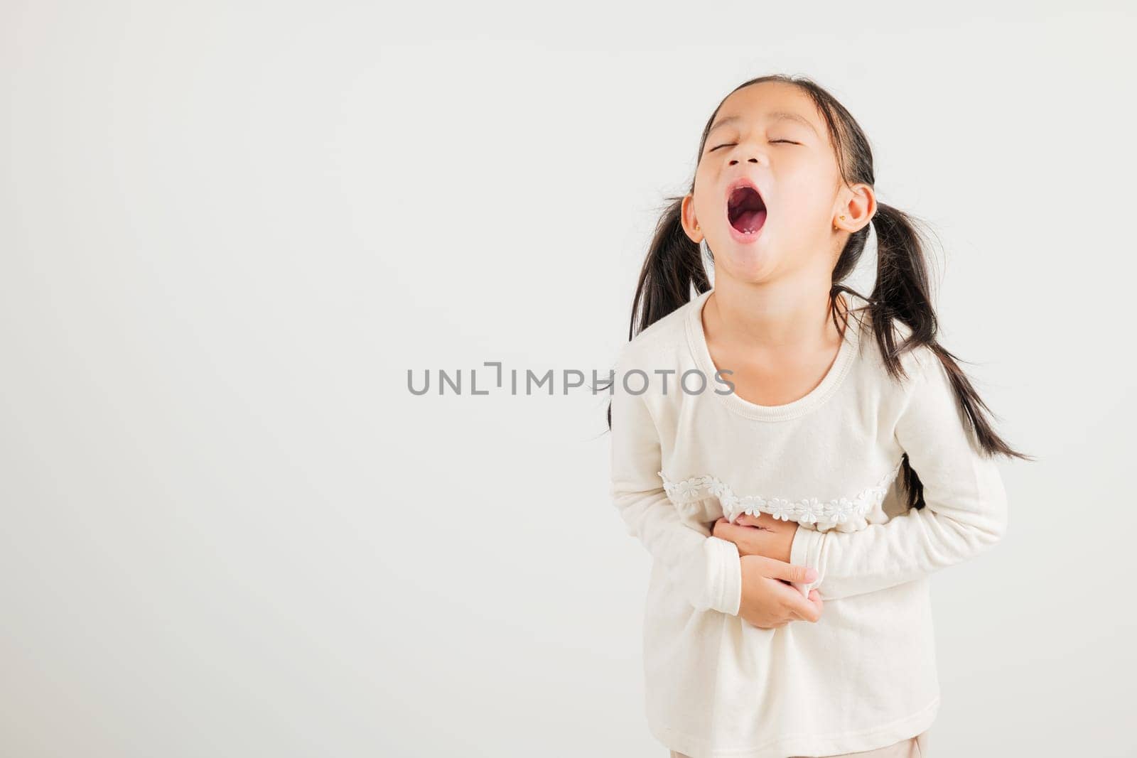 Portrait of Asian young kid girl has stomachache, kindergarten child abdominal pain suffering from stomach ache, studio shot isolated on white background, food poisoning, Health and medical gastritis