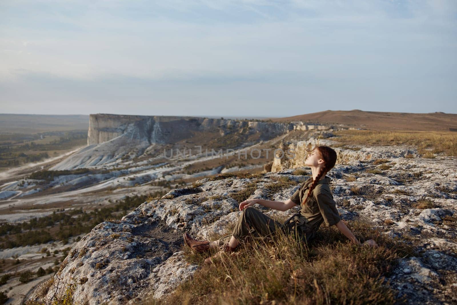 Tranquil woman contemplating majestic mountain range from cliff edge in valley with travel adventure and exploration theme