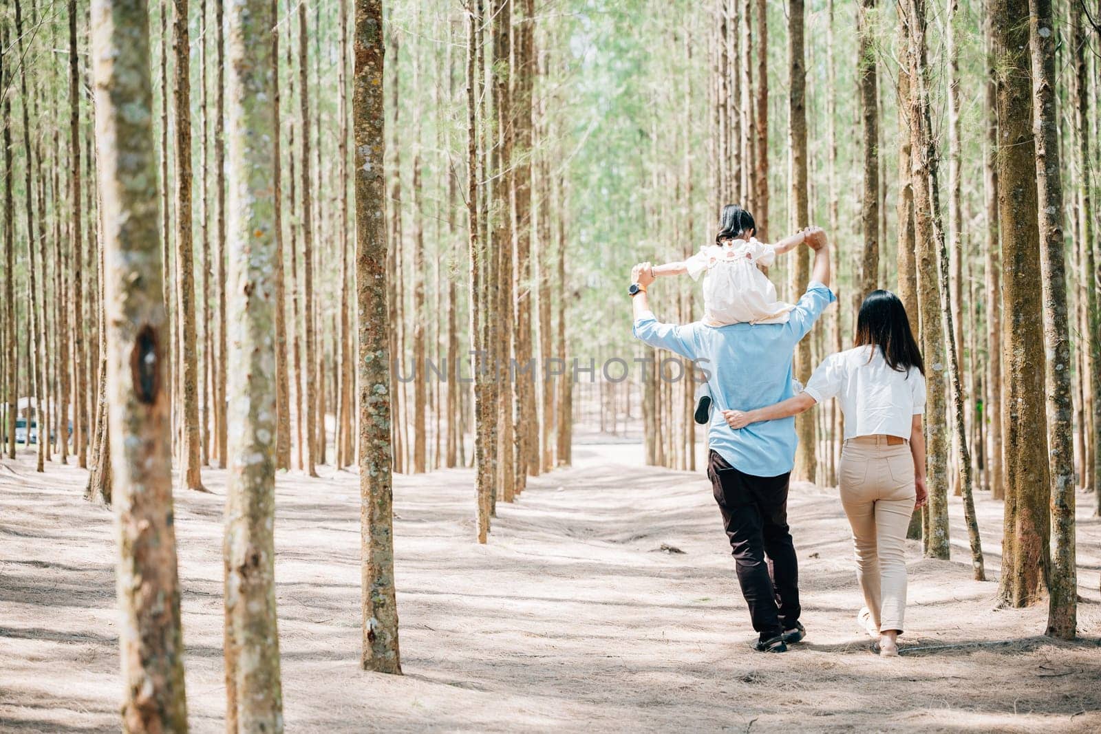 Family father carrying young girl shoulders while walking in forest with mother, Happy Asian family with adorable children in weekend, shoulder carry and happy family kid, dad and mom enjoy together