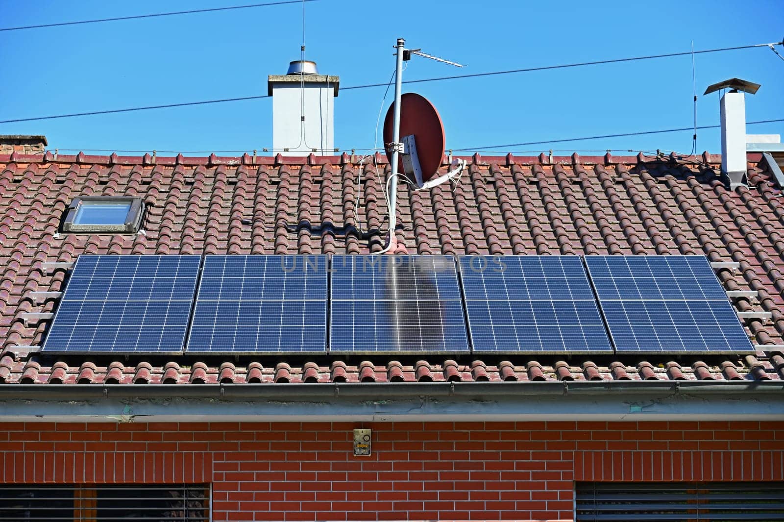 Family house with solar panels on the roof. Home photovoltaic power plant. Concept for industry and green cheaper electricity from renewable sources.
