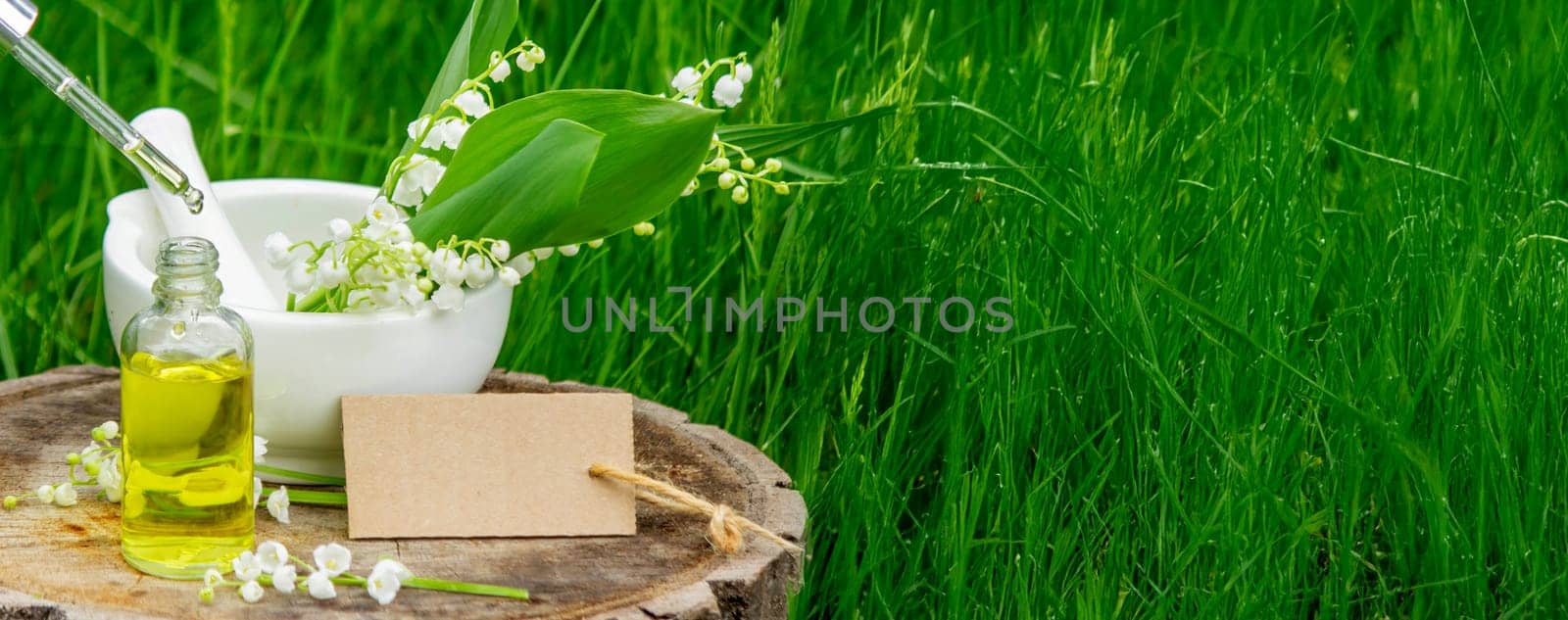 Glass bottle of lily of the valley essential oil with fresh flowers