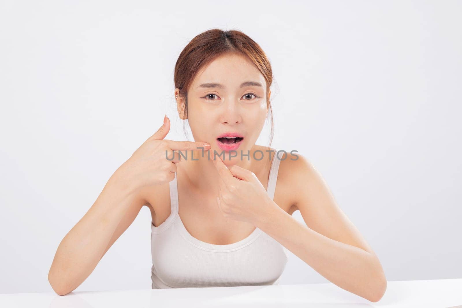 Acne becomes visible concern as this young woman gently presses acne on her forehead, dealing with skin blemishes and blackhead issues while focusing on her skincare routine. isolated white background