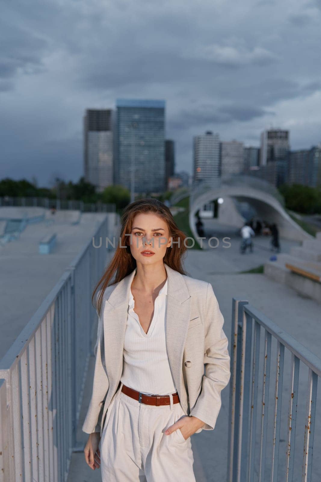 A stylish woman in a tailored business suit poses confidently in an urban setting, exuding professionalism and sophistication with a contemporary city skyline.