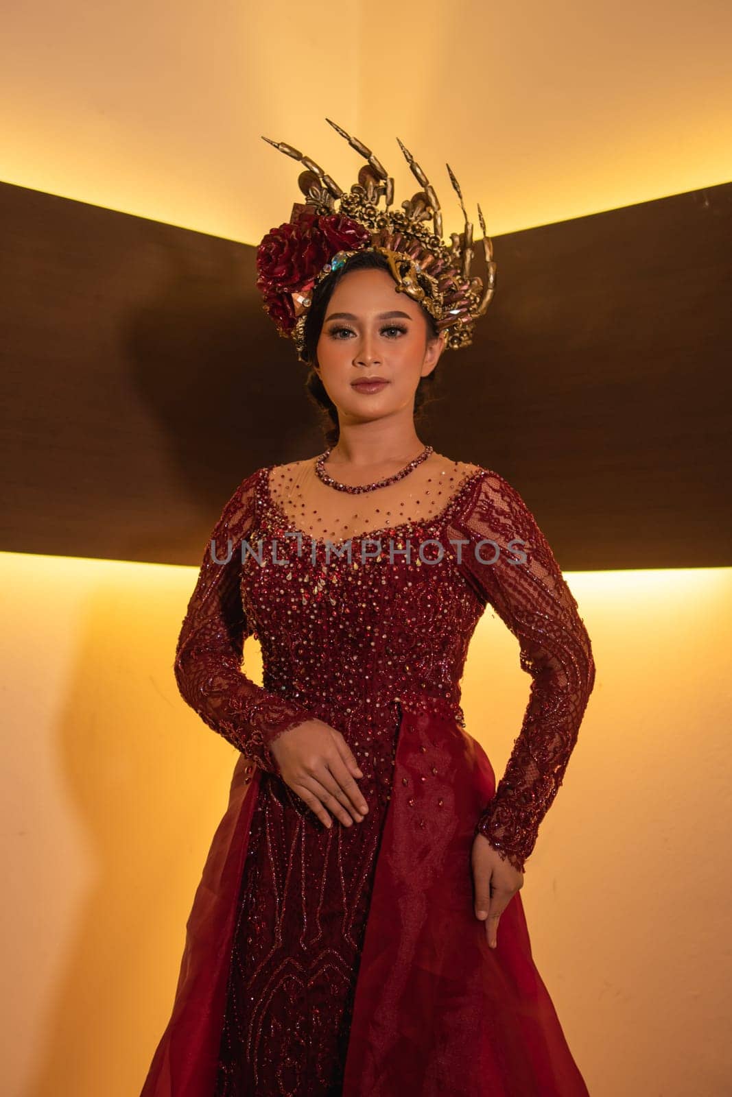 Asian woman in red dress posing with a gold crown on her head inside the studio