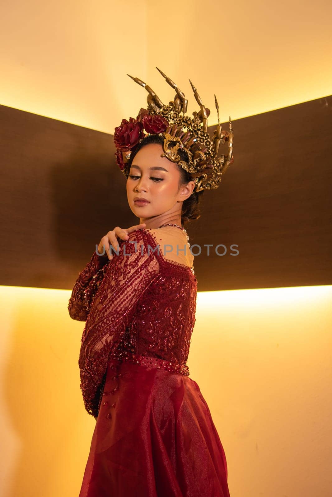 Asian woman in red dress posing with a gold crown on her head inside the studio