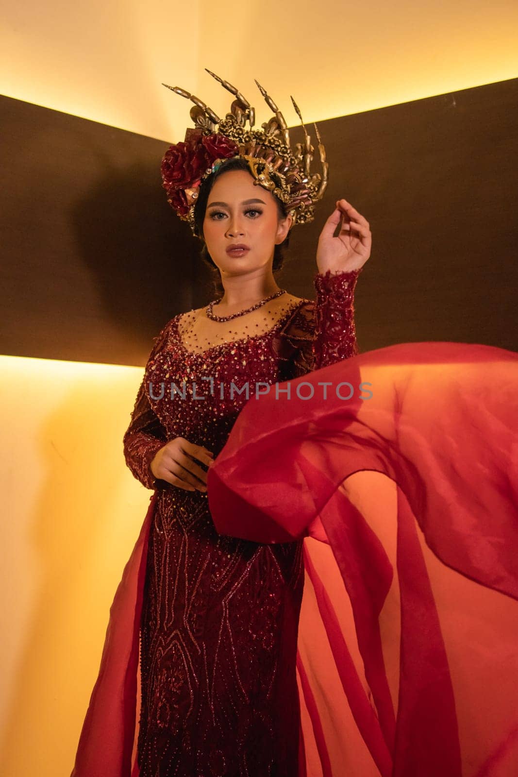 A beautiful Asian woman swings the red fabric tail while wearing a red wedding dress before the wedding ceremony