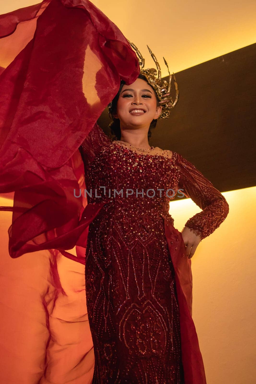 Princess wearing a red dress with the gold crown on her head in front of the lighting in the background