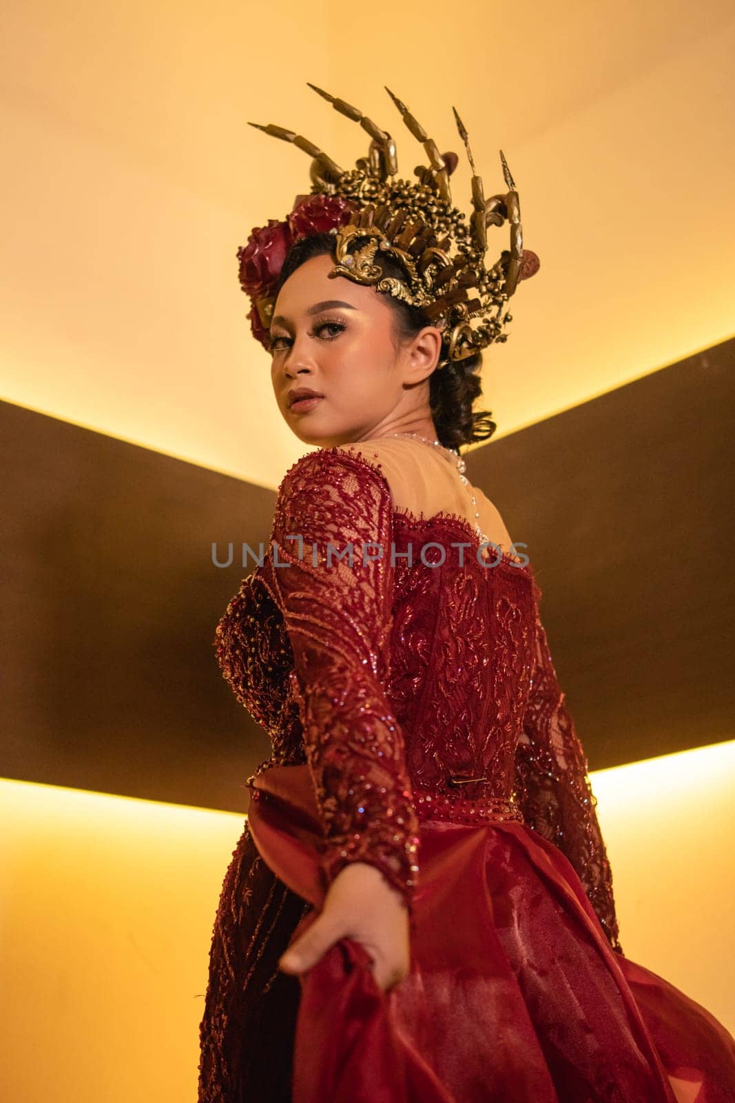 Princess wearing a red dress with the gold crown on her head in front of the lighting in the background