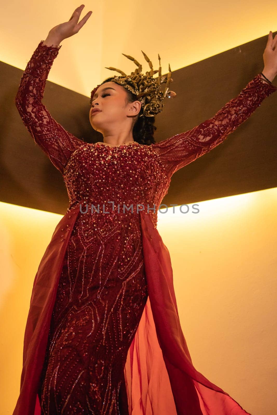 Princess wearing a red dress with the gold crown on her head in front of the lighting in the background