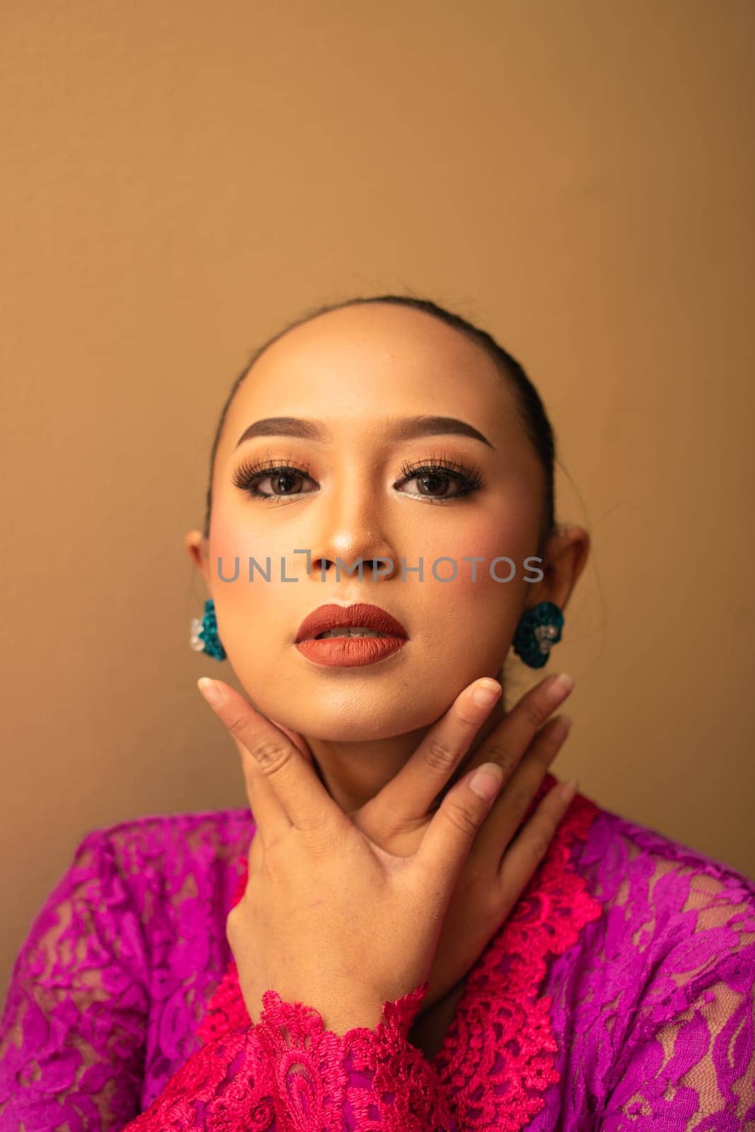 Asian woman touching her neck and feeling sexy with herself while posing inside the cream room