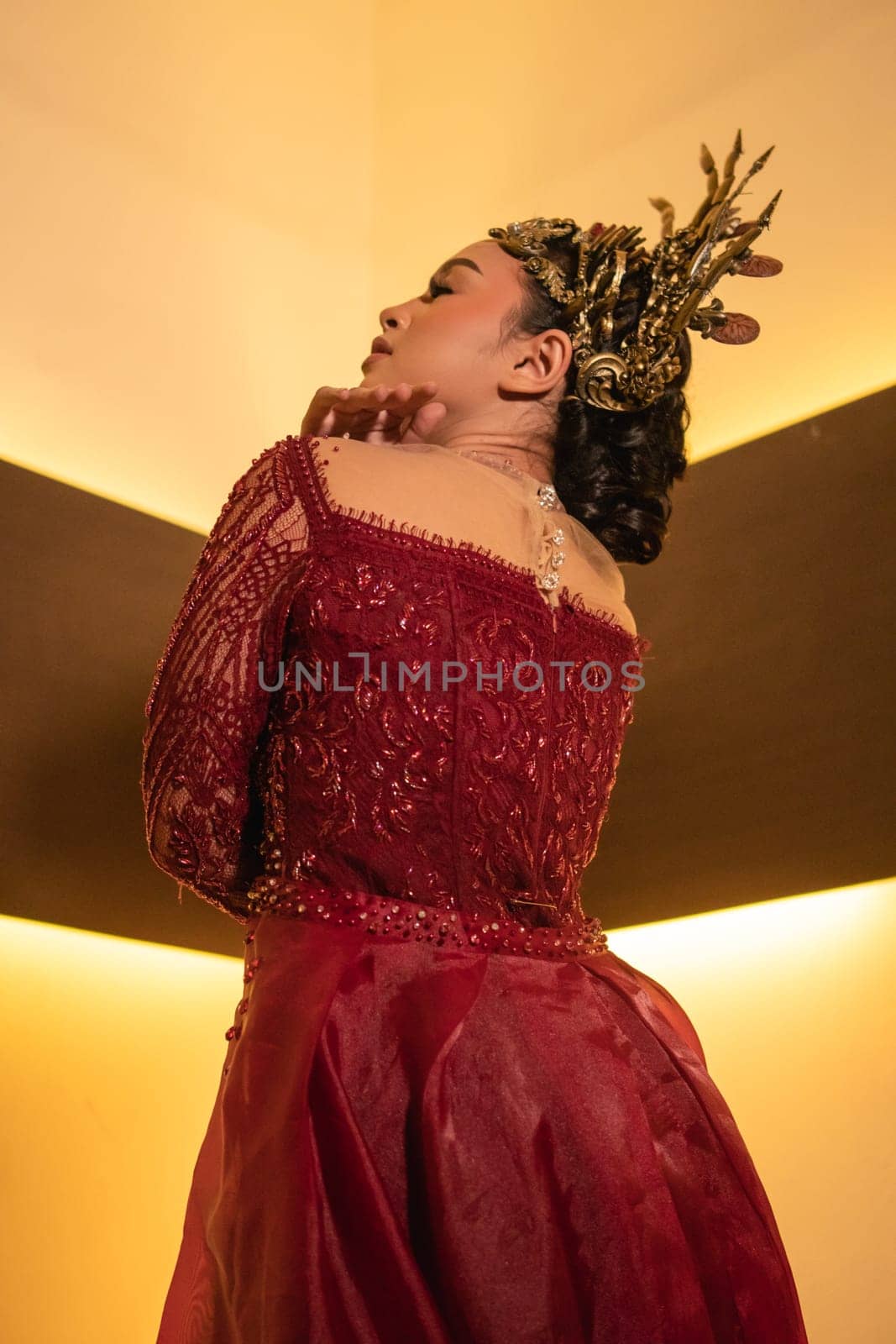 Asian woman in red dress posing with a gold crown on her head inside the studio