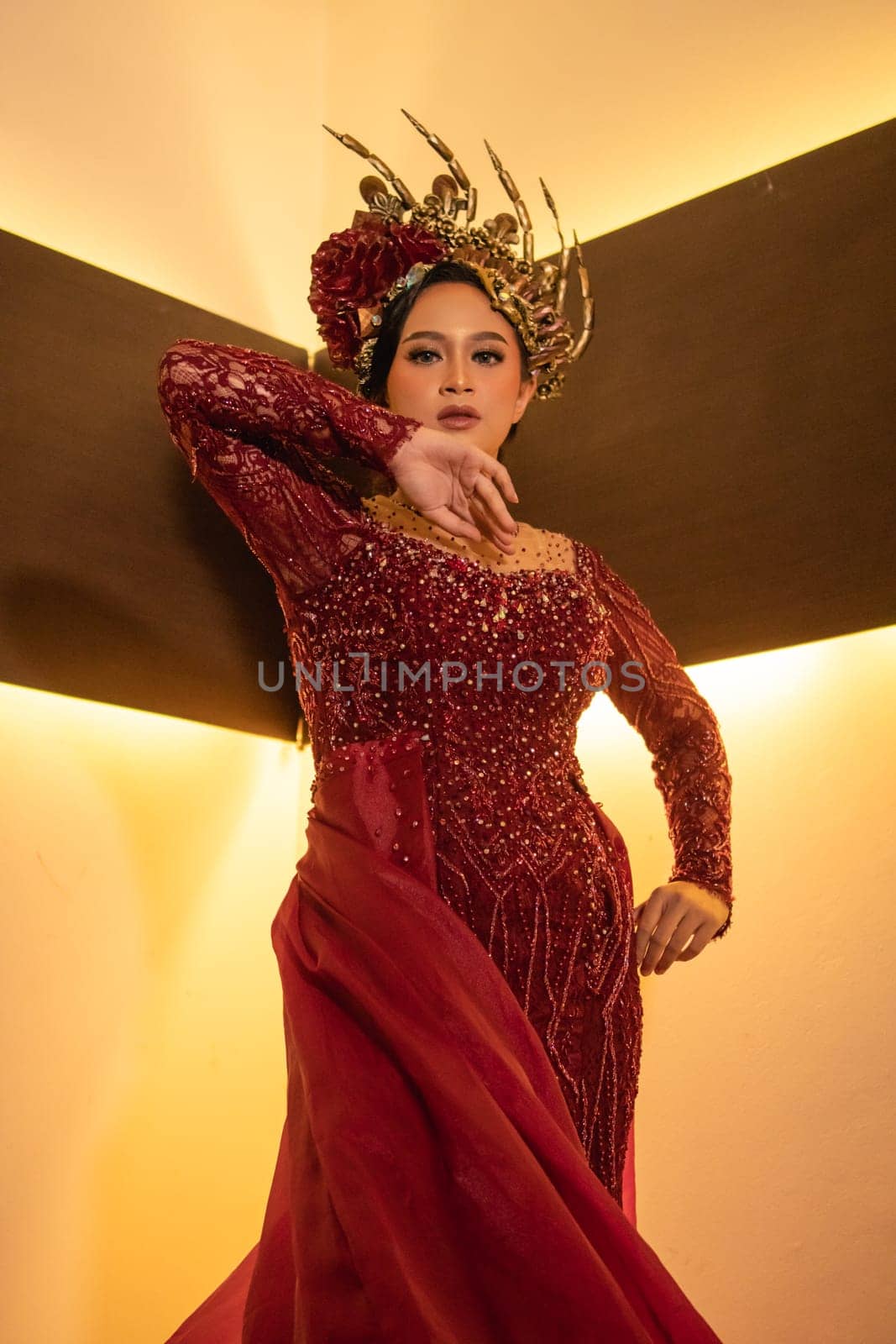 Asian woman in red dress posing with a gold crown on her head inside the studio