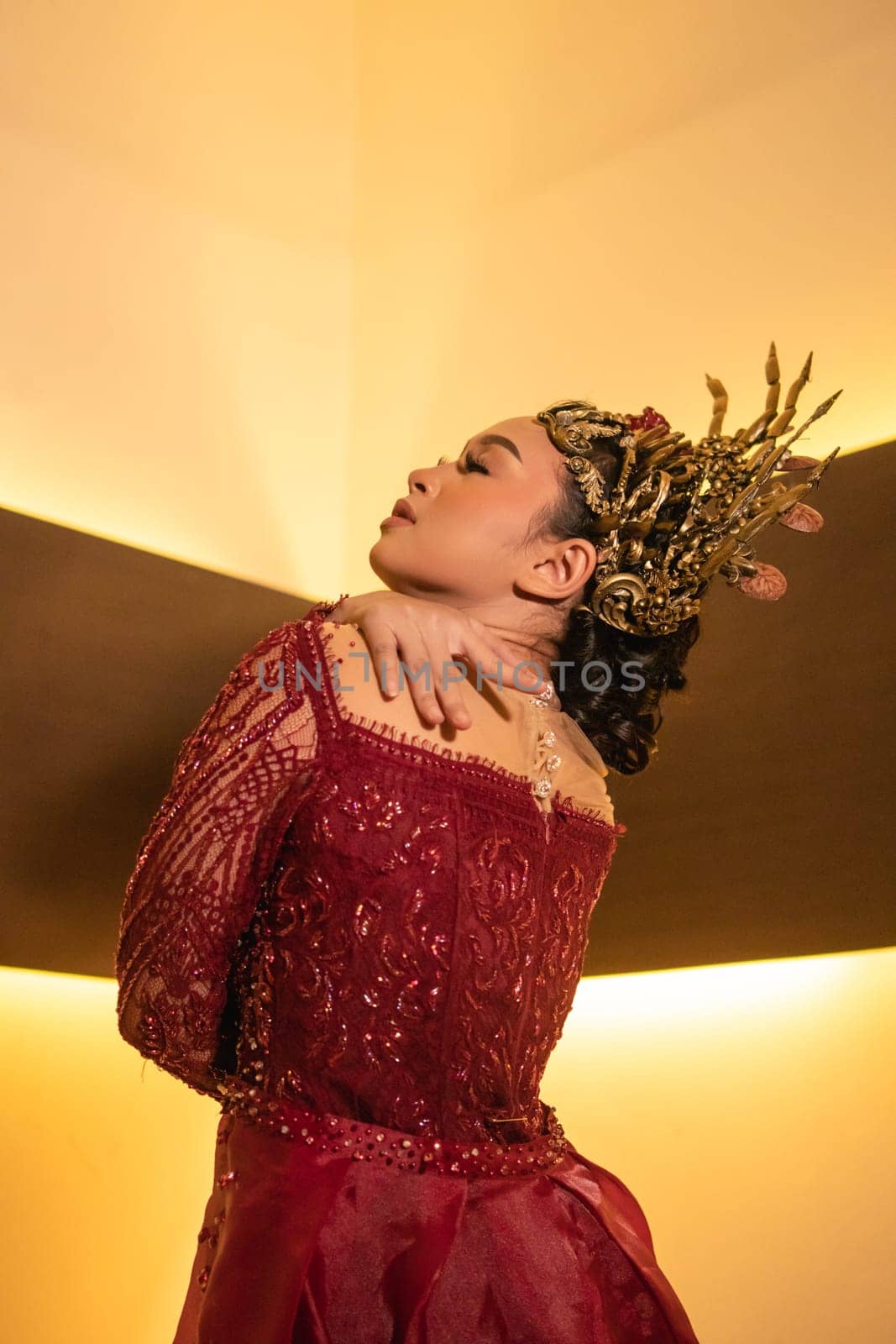 Asian woman in red dress posing with a gold crown on her head inside the studio