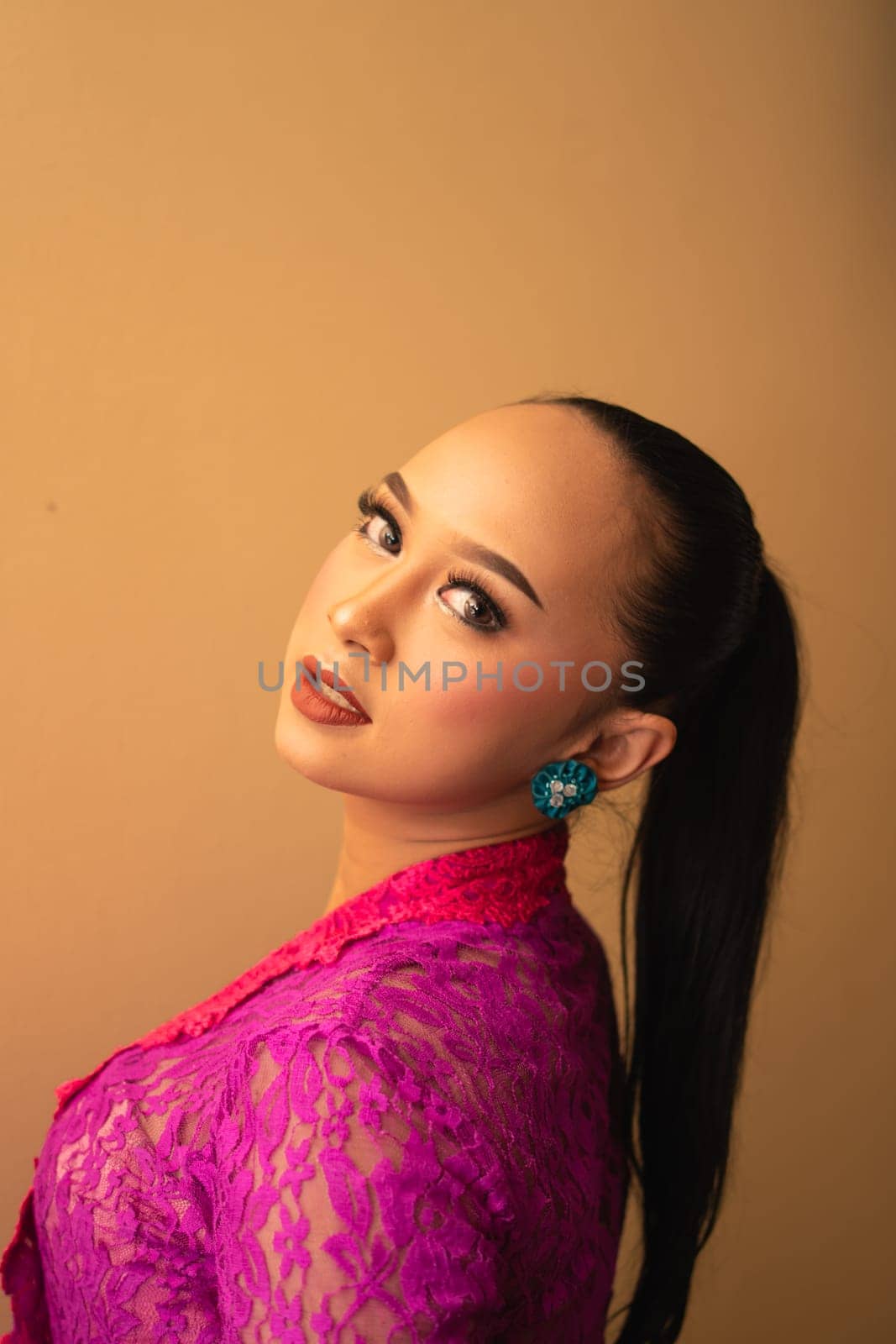 Javanese woman with black hair wearing makeup and a pink dress called kebaya in Indonesia festival event
