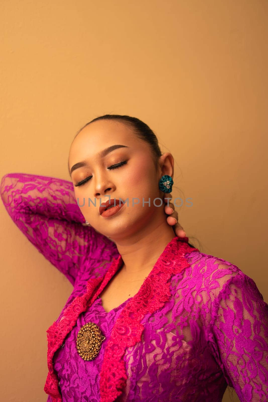 Asian woman touches her head while posing with makeup inside the studio