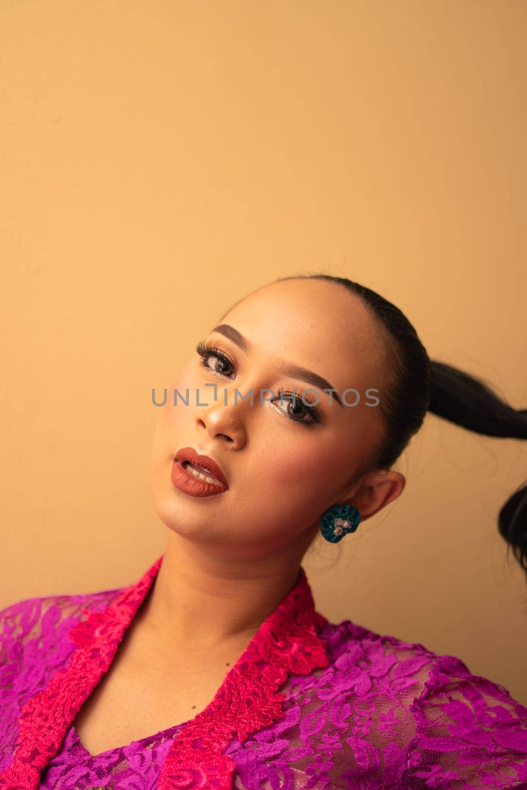 Javanese woman with black hair wearing makeup and a pink dress called kebaya in Indonesia festival event