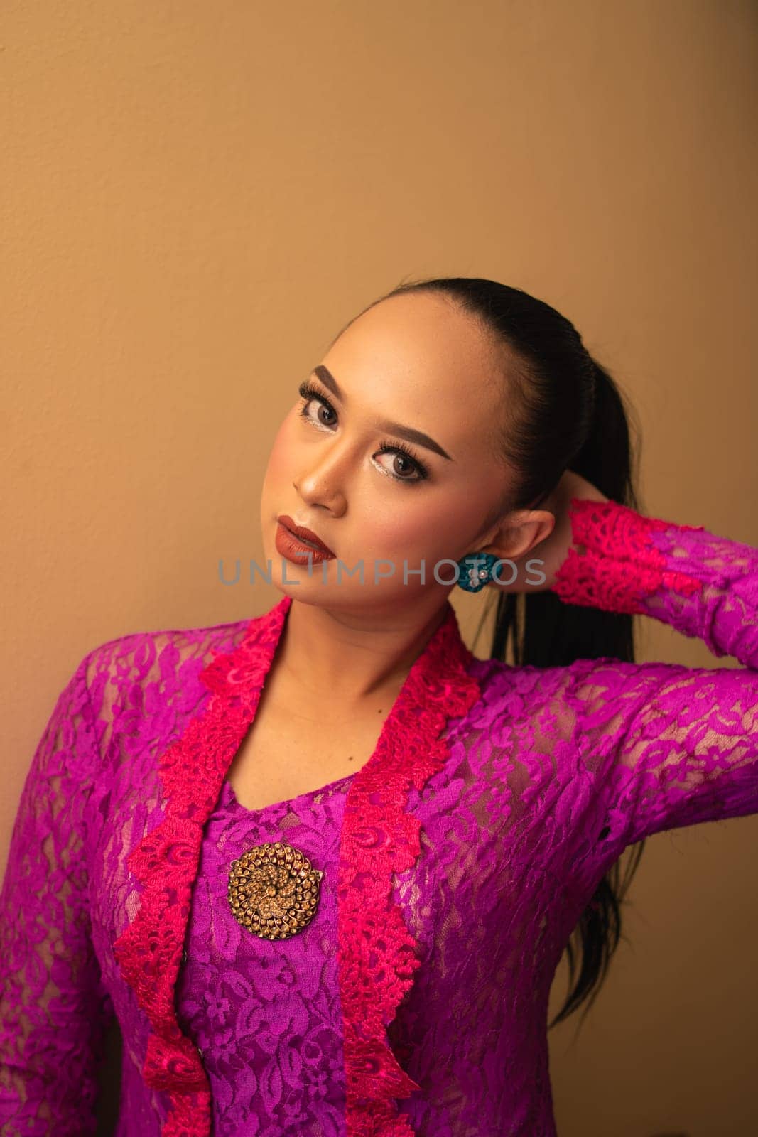 Asian woman touches her head while posing with makeup inside the studio