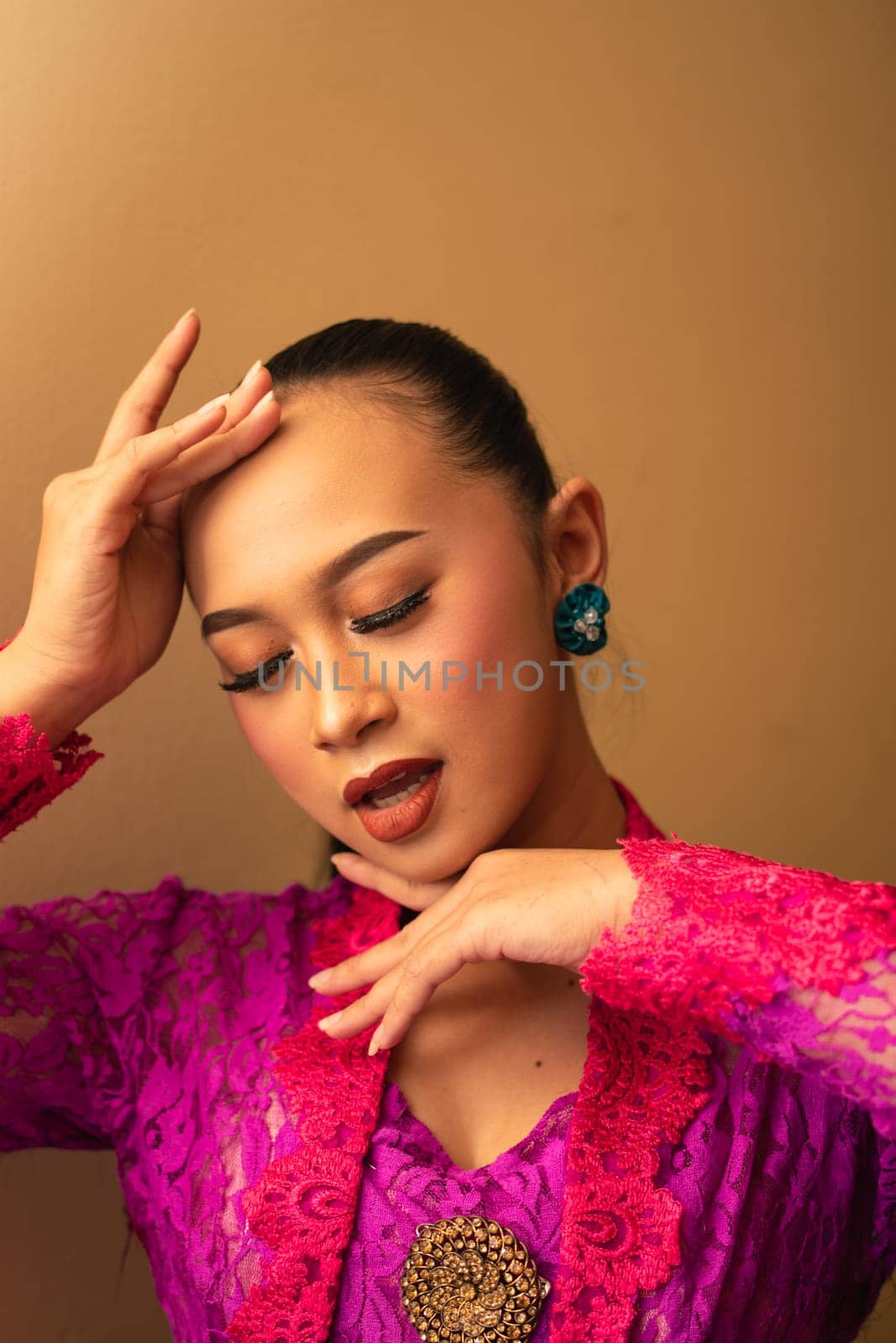 Asian woman touches her head while posing with makeup inside the studio
