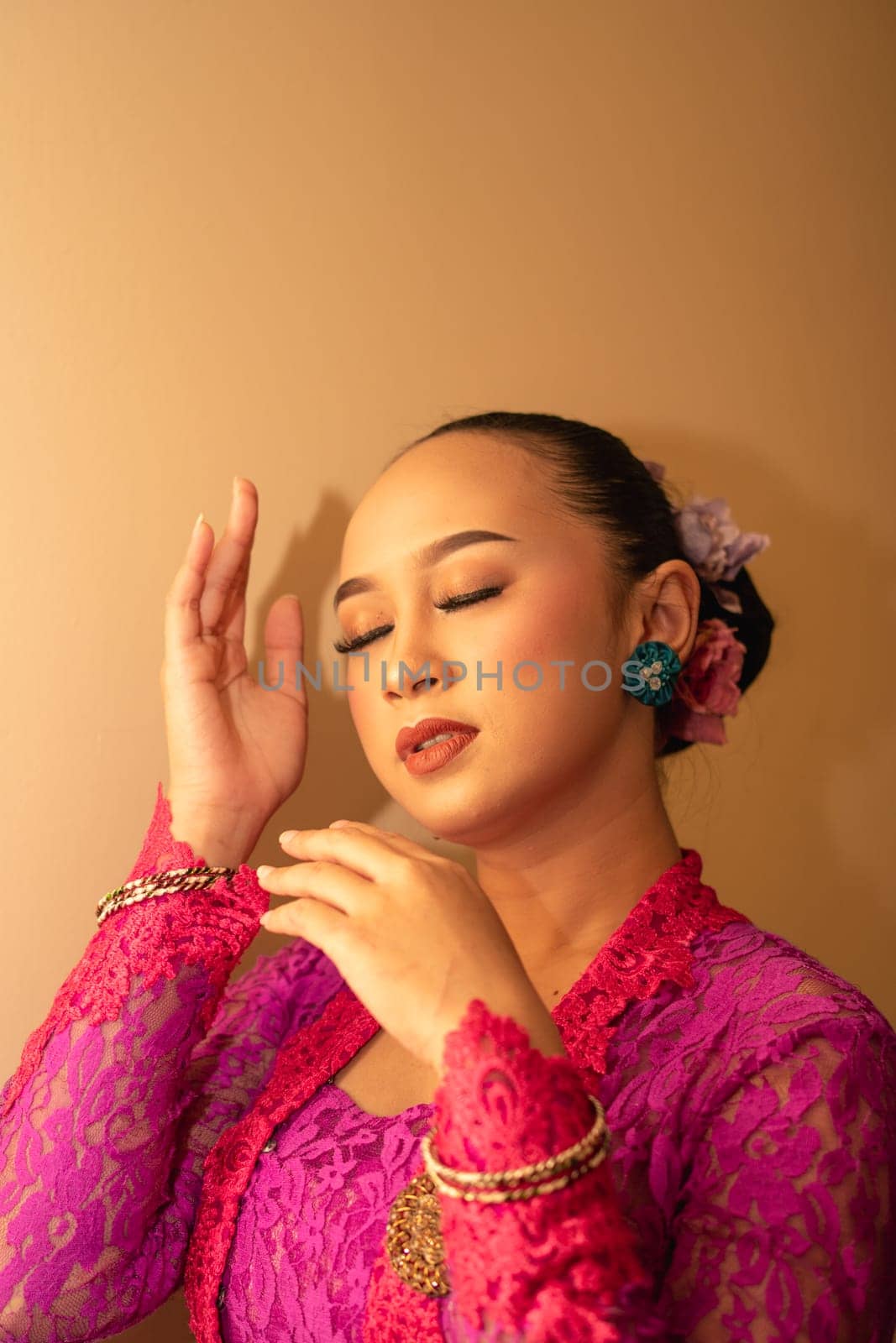 Balinese woman wearing a pink dress during the praying process in the temple at the Bali festival