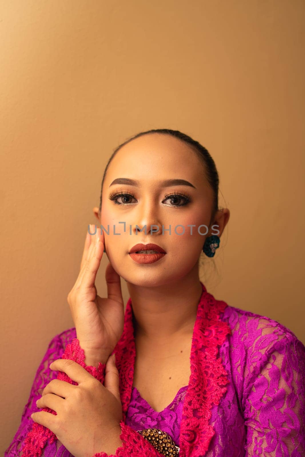 Asian woman touches her head while posing with makeup inside the studio