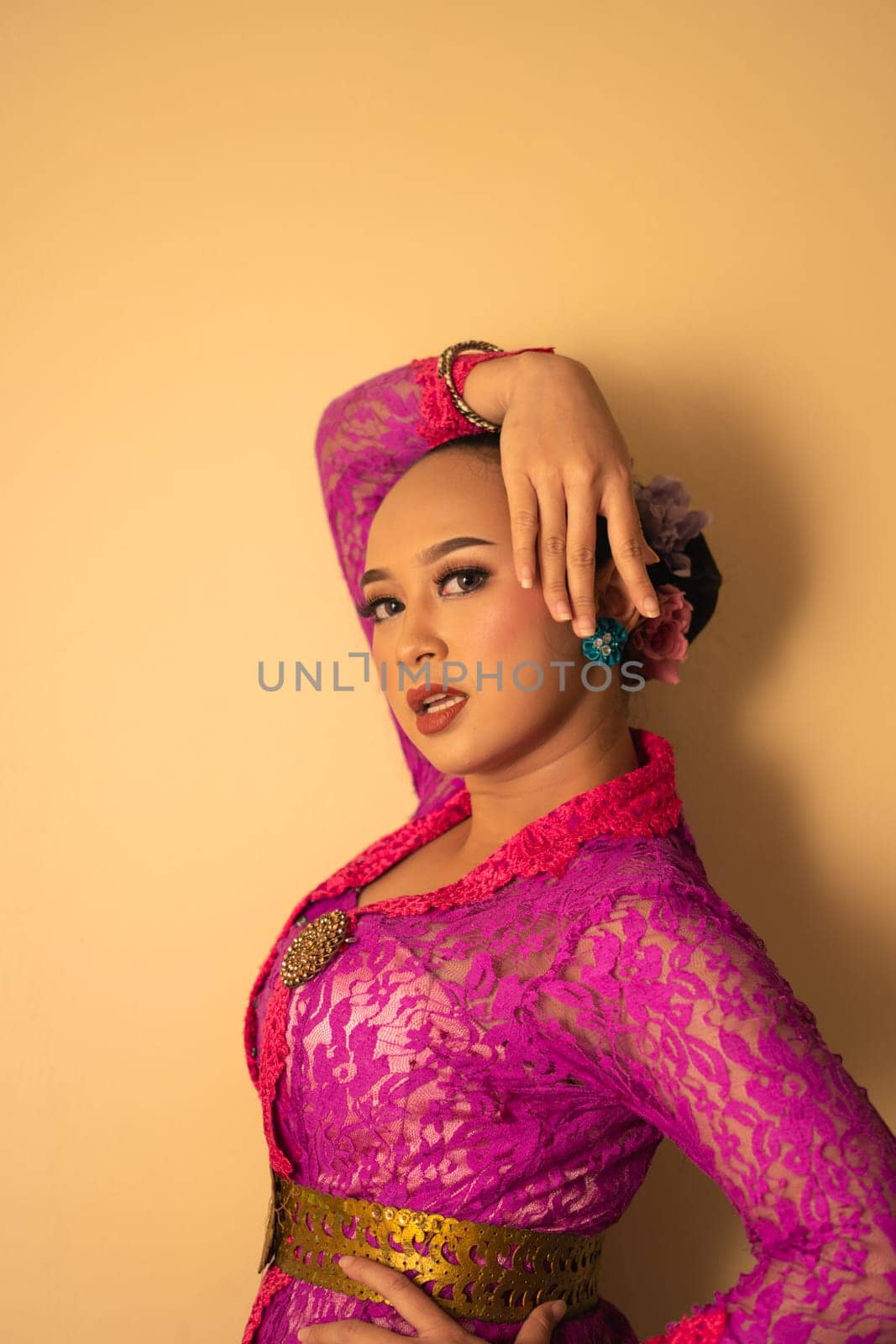 Balinese mother wearing a pink dress called kebaya and make-up before praying in the temple