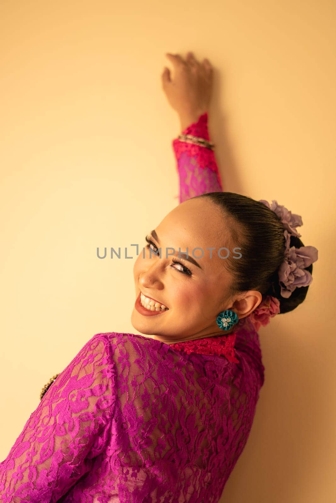 Balinese mother wearing a pink dress called kebaya and make-up before praying in the temple
