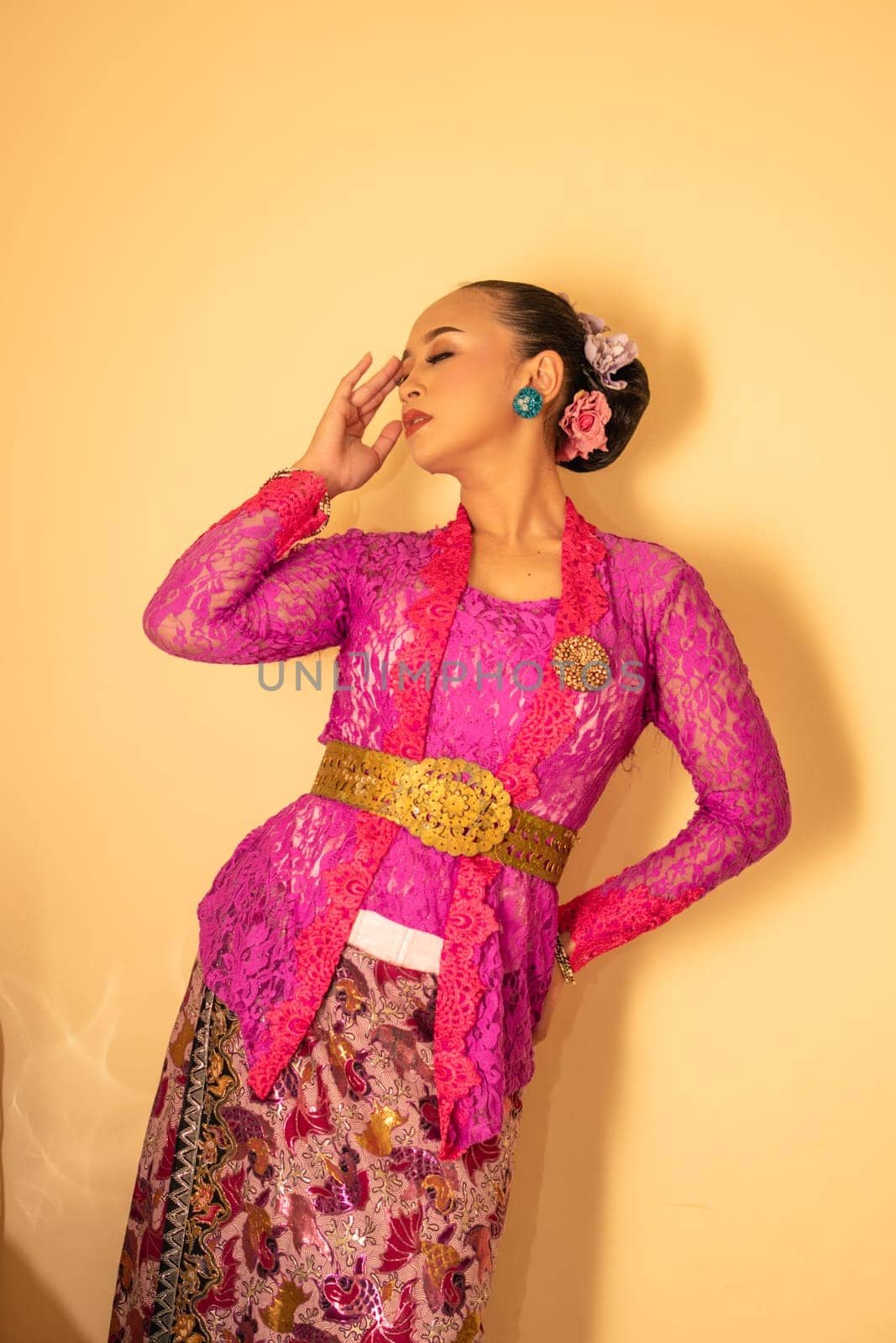 Balinese woman wearing a pink dress called kebaya from Indonesia's traditional dresses inside the temple