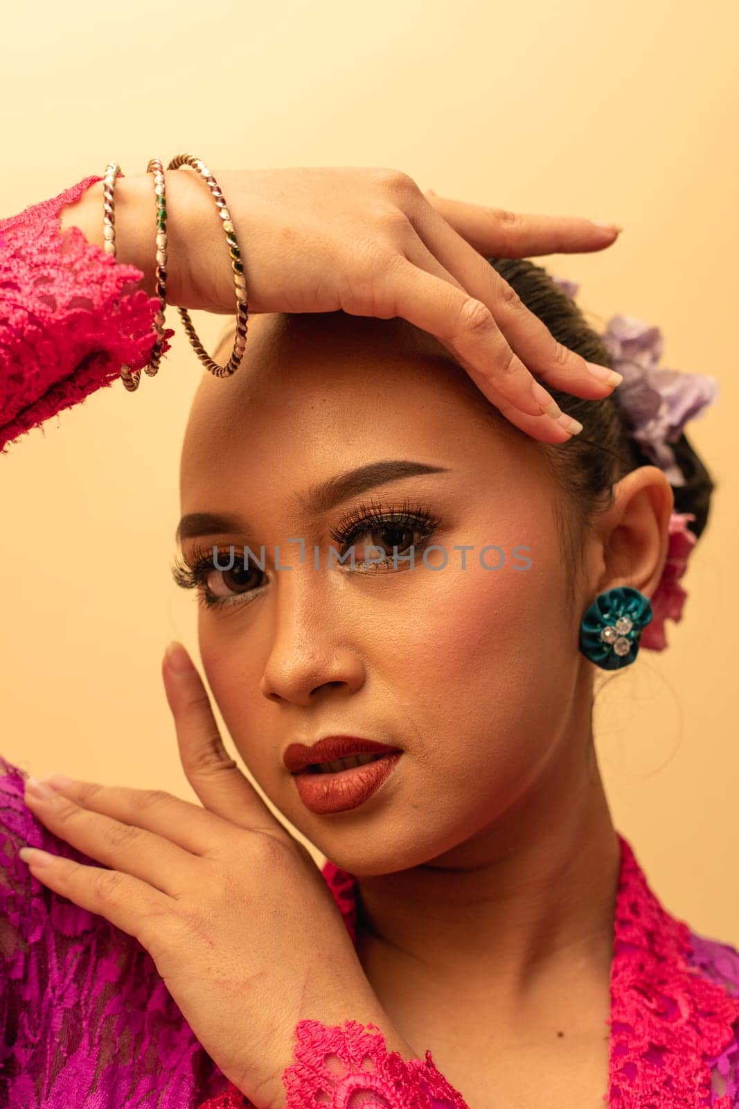 beautiful Balinese woman wearing makeup in a pink dress while posing with exotic hands inside the studio
