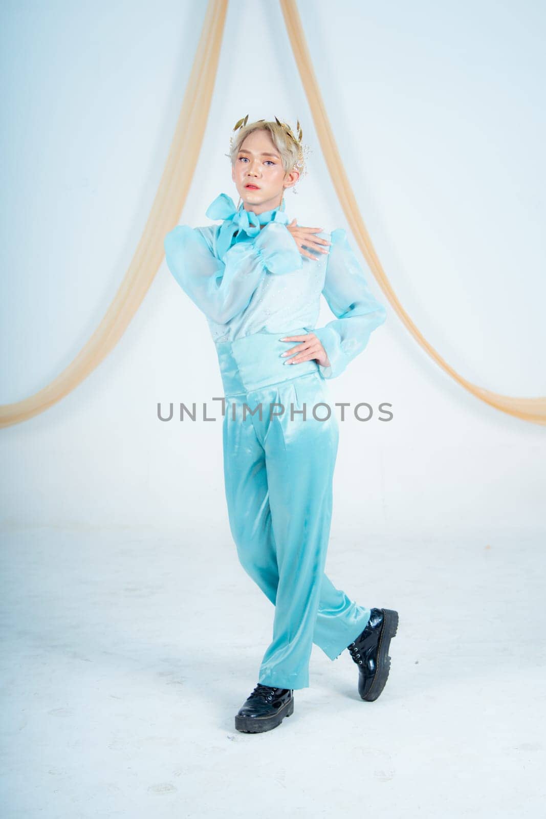 an Asian woman posing elegantly in a blue costume in a white room