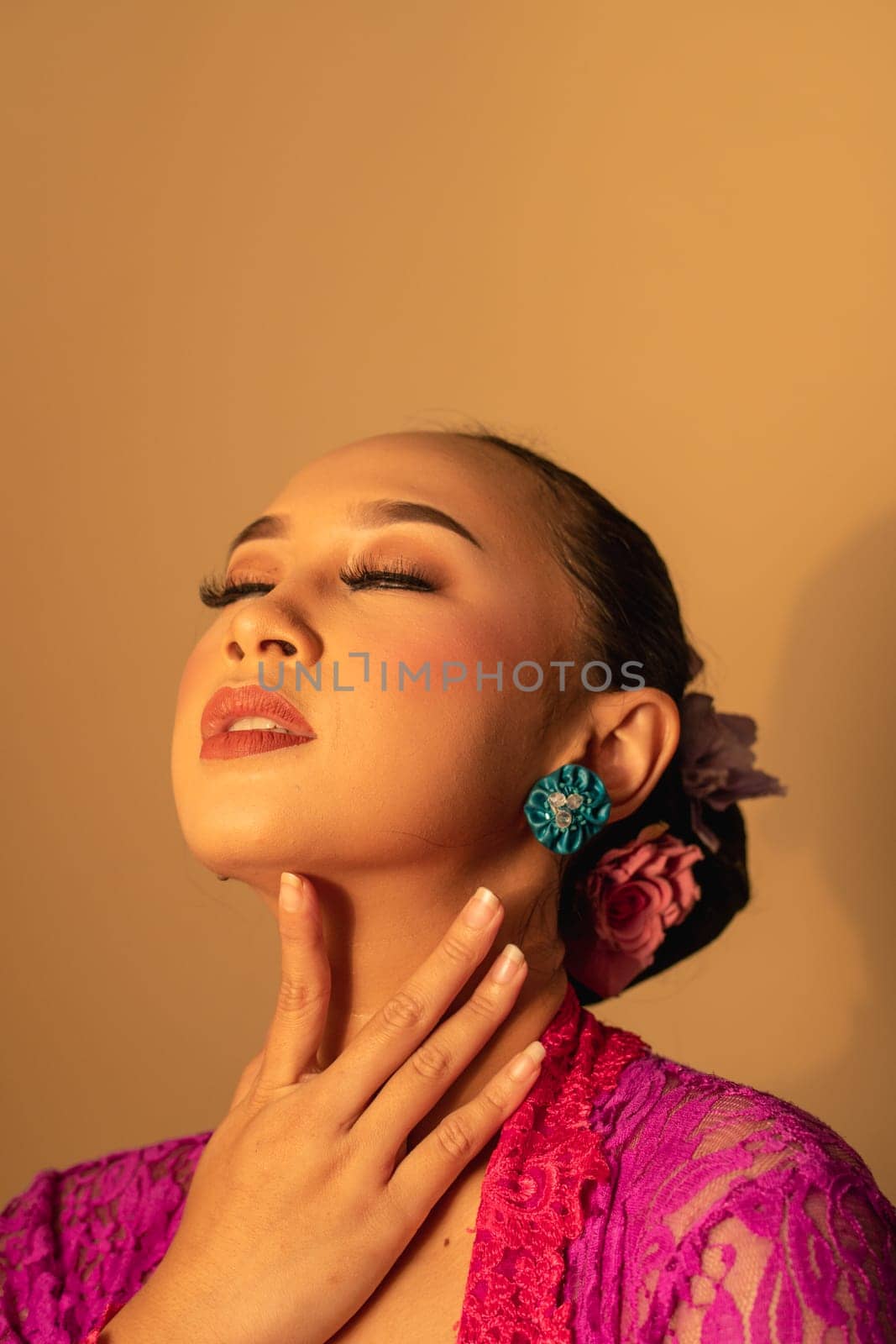 Sexy Asian woman wearing a pink dress called kebaya with a hot pose inside the studio
