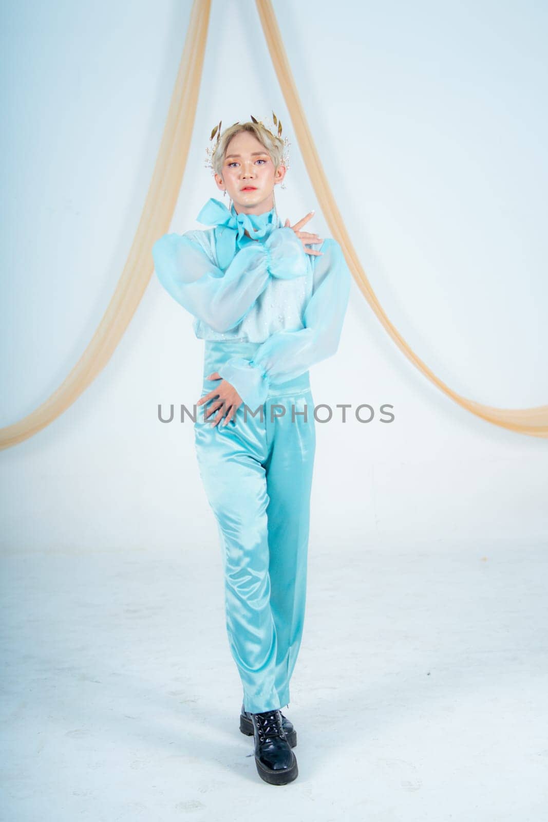 an Asian woman posing elegantly in a blue costume in a white room