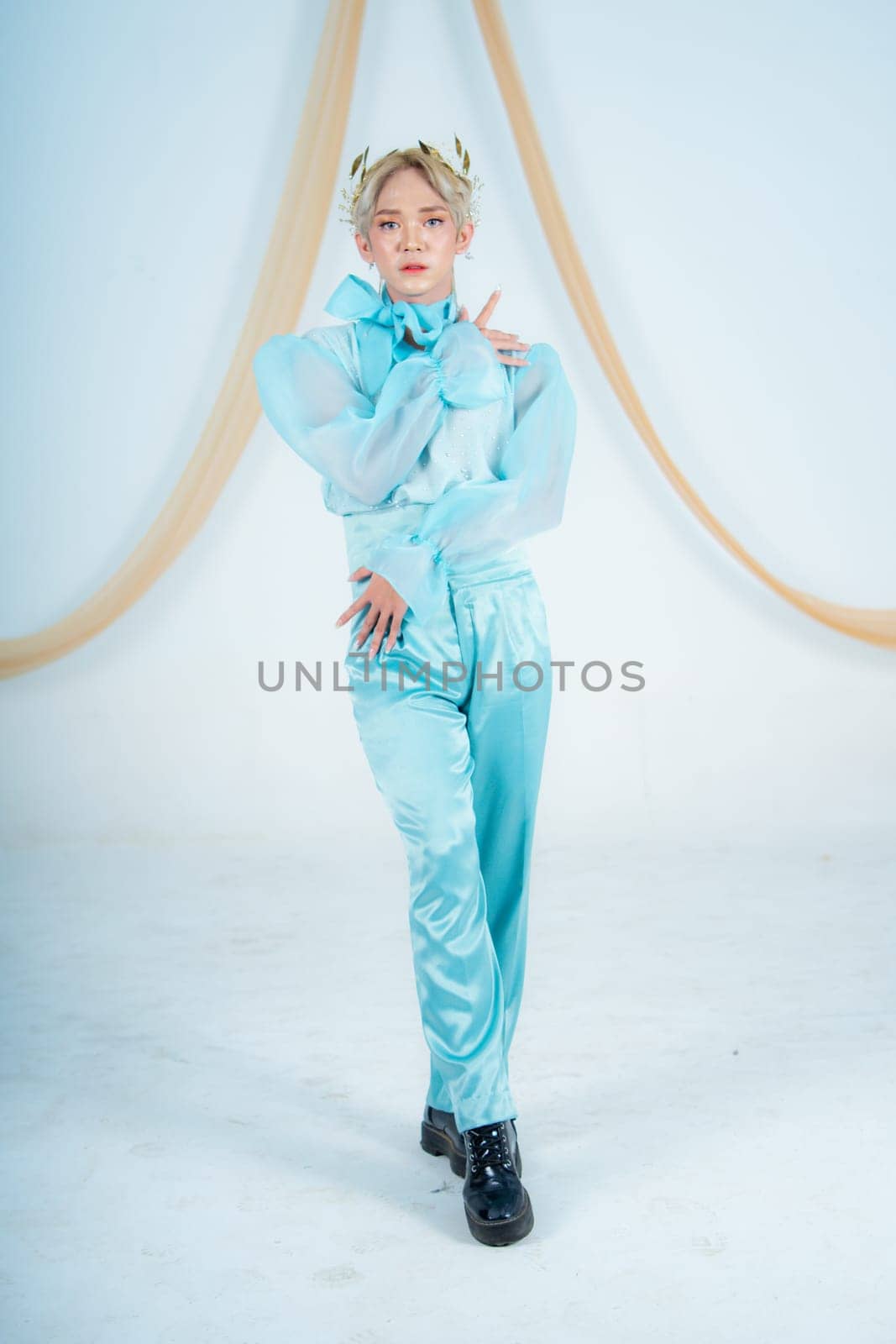an Asian woman posing elegantly in a blue costume in a white room